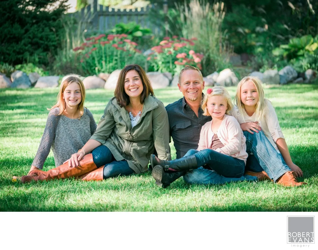 Informal summer family portrait of parents and their three daughters photographed in their own backyard, creating a natural and personal setting for family photography.