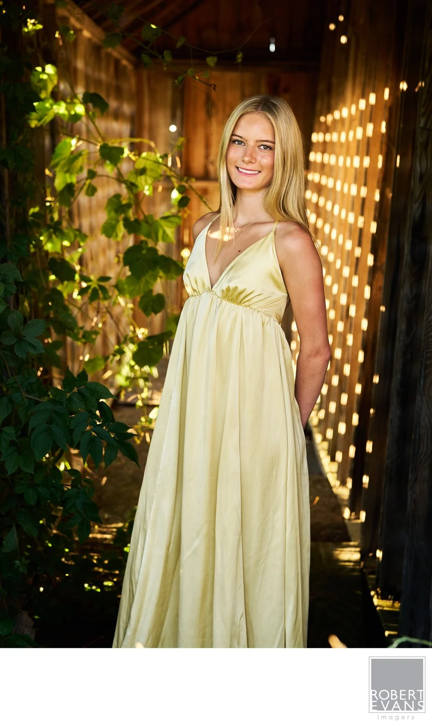 Natural outdoor high school senior portrait featuring beautiful golden light, a flowing yellow dress and a rustic garden setting in the Twin Cities.