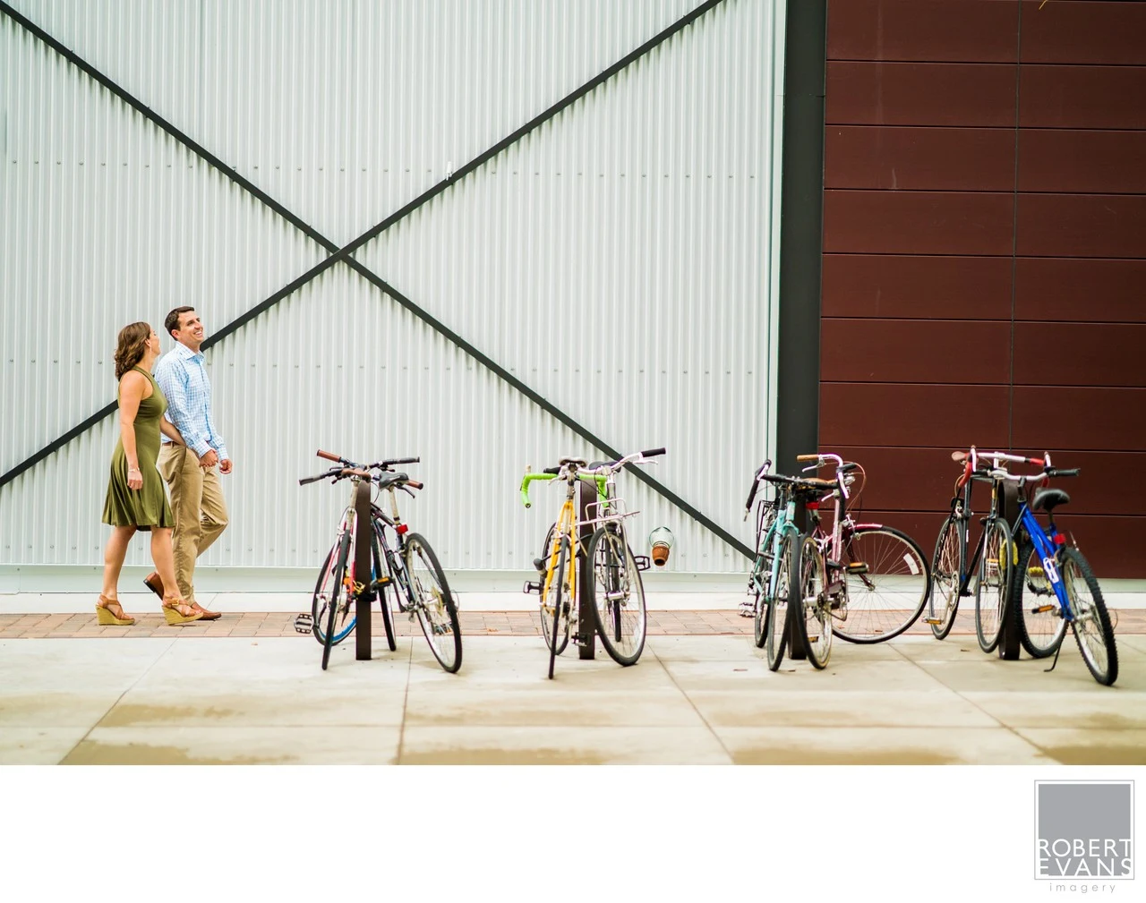 A natural portrait of a couple walking together among bicycles and modern architecture, using the environment and negative space to create a relaxed, contemporary image.