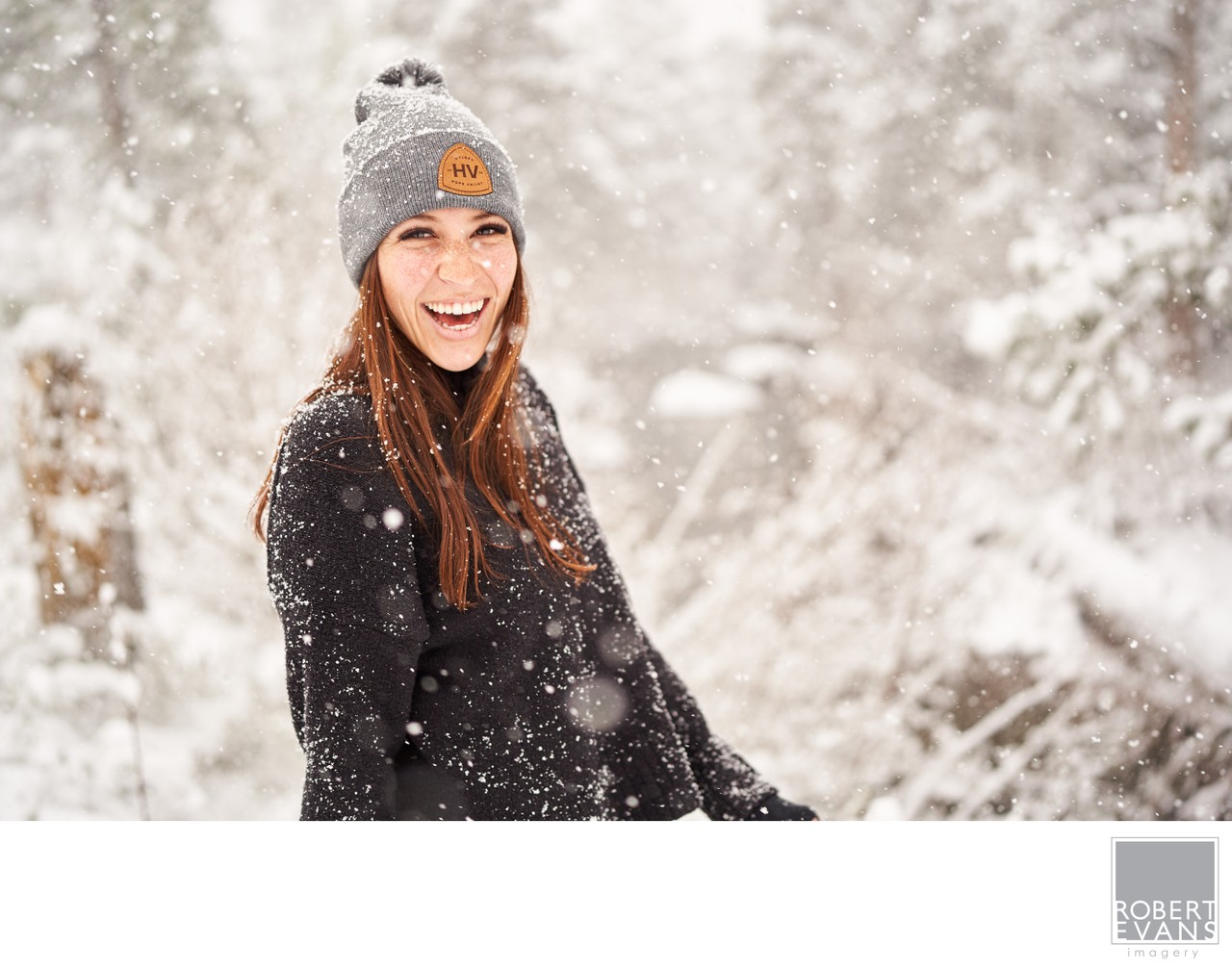 A joyful female outdoor winter portrait photographed during a Minnesota snowfall, combining natural expression with the beauty and atmosphere of the season.