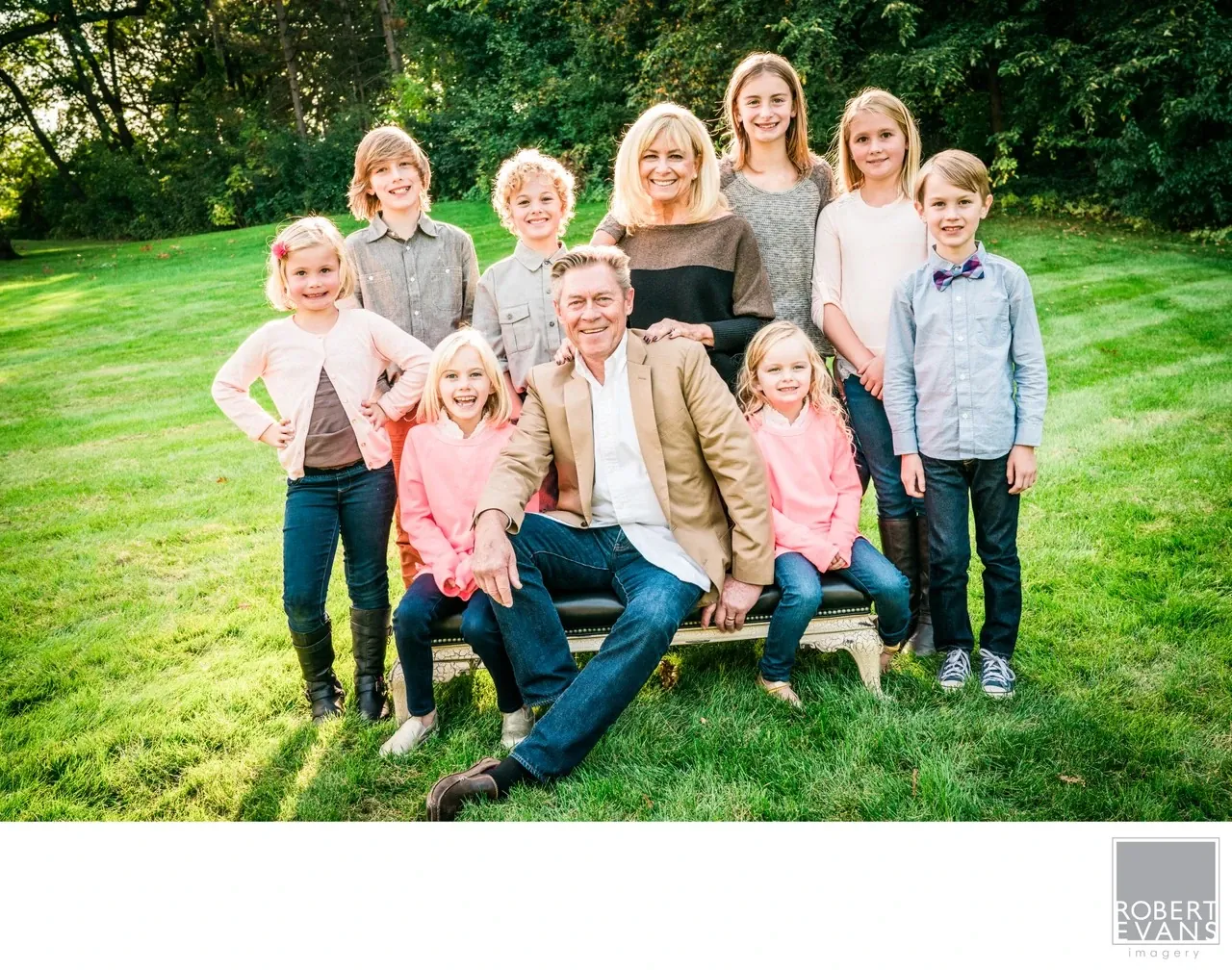 A joyful outdoor portrait of grandparents surrounded by their grandchildren, capturing the relationships, personalities and connection of a multigenerational family.
