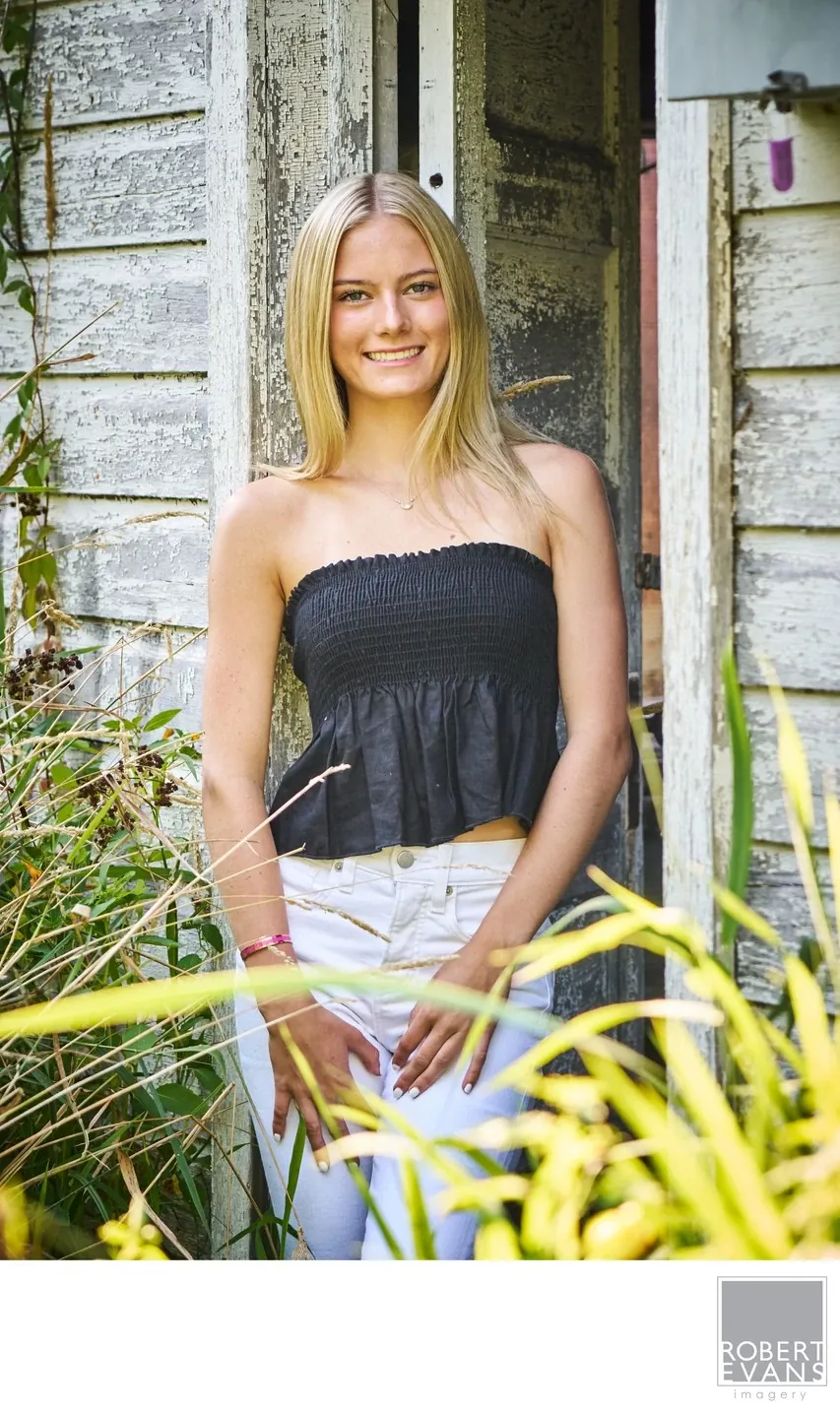 A relaxed high school senior portrait using a rustic setting and natural surroundings to create a simple, timeless image centered on personality.