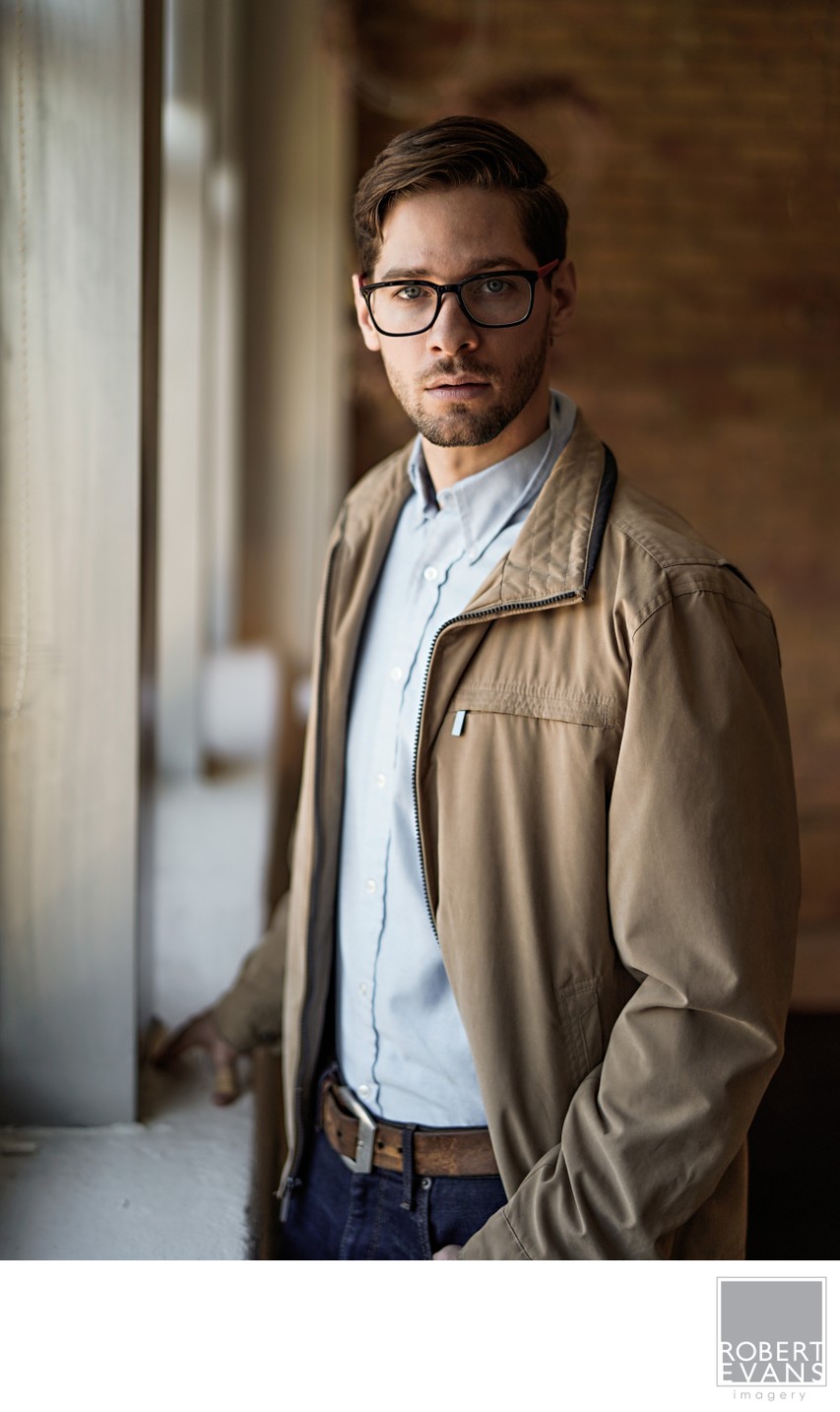 Natural professional portrait of a man photographed with soft window light and shallow depth of field, creating a modern, relaxed alternative to a traditional studio headshot.
