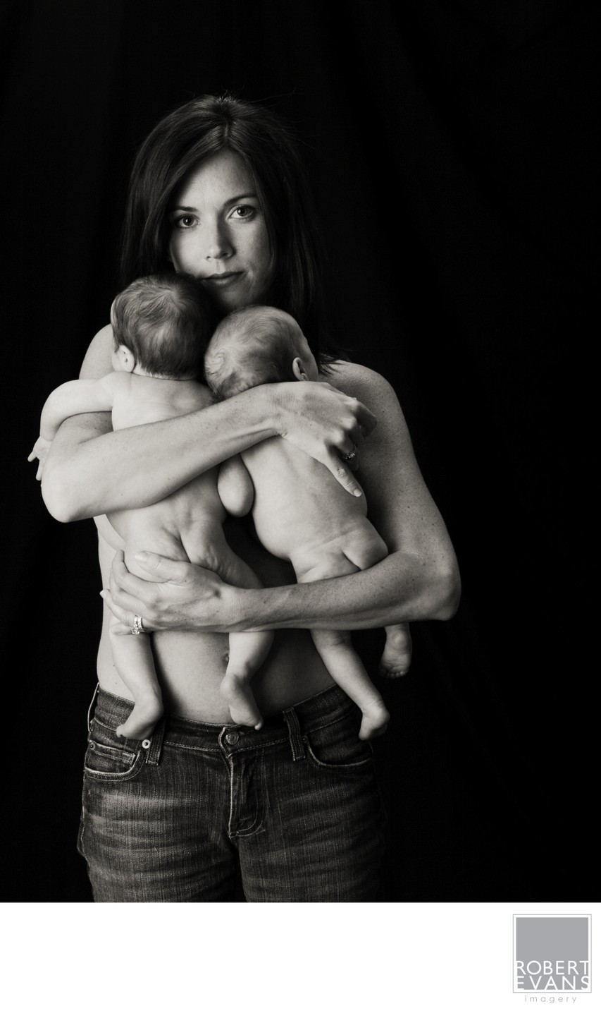 Intimate black and white portrait of a mother holding her twin babies close.