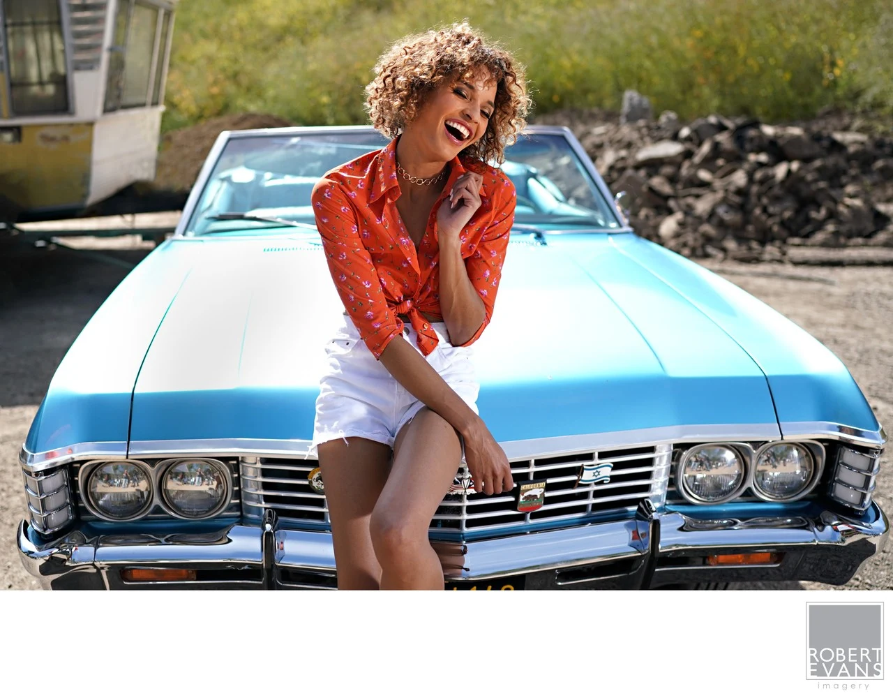 Vibrant lifestyle portrait featuring a woman posed with a classic blue convertible.
