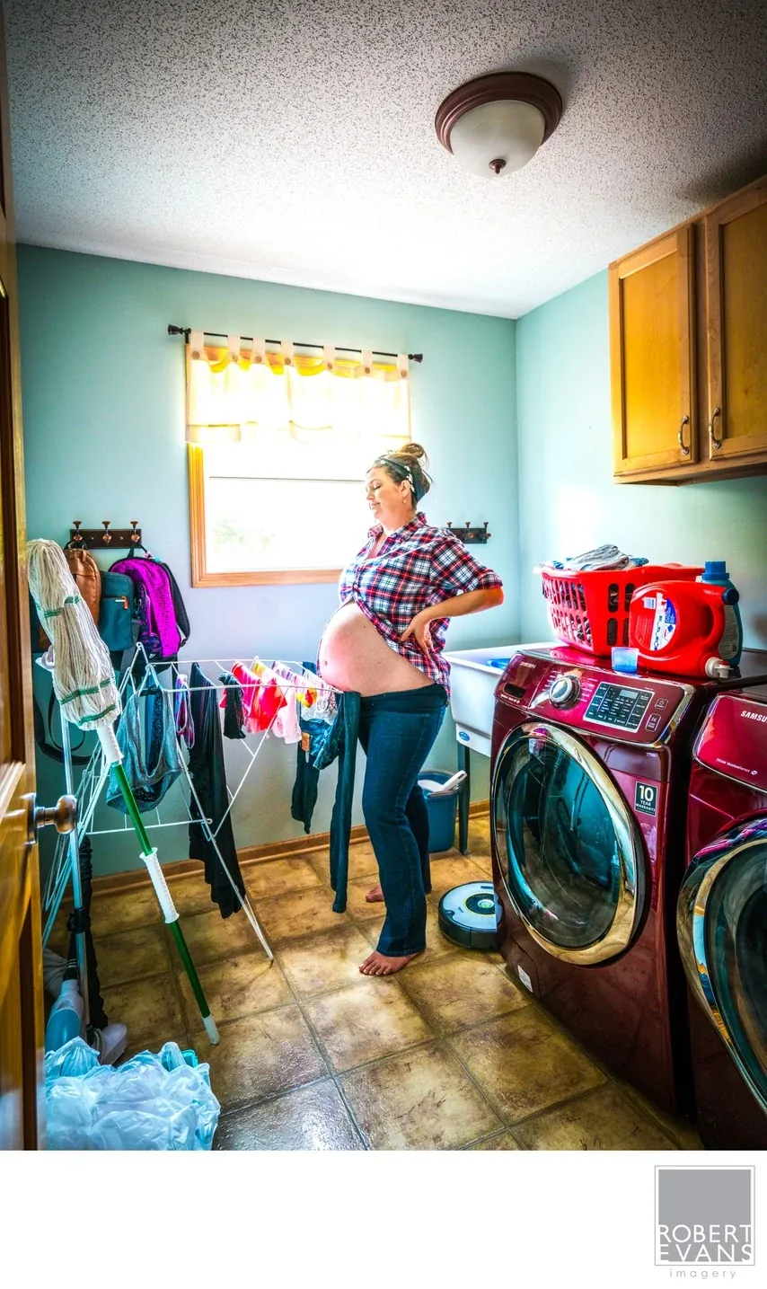 A woman holds a child in a colorful laundry room filled with everyday household details.