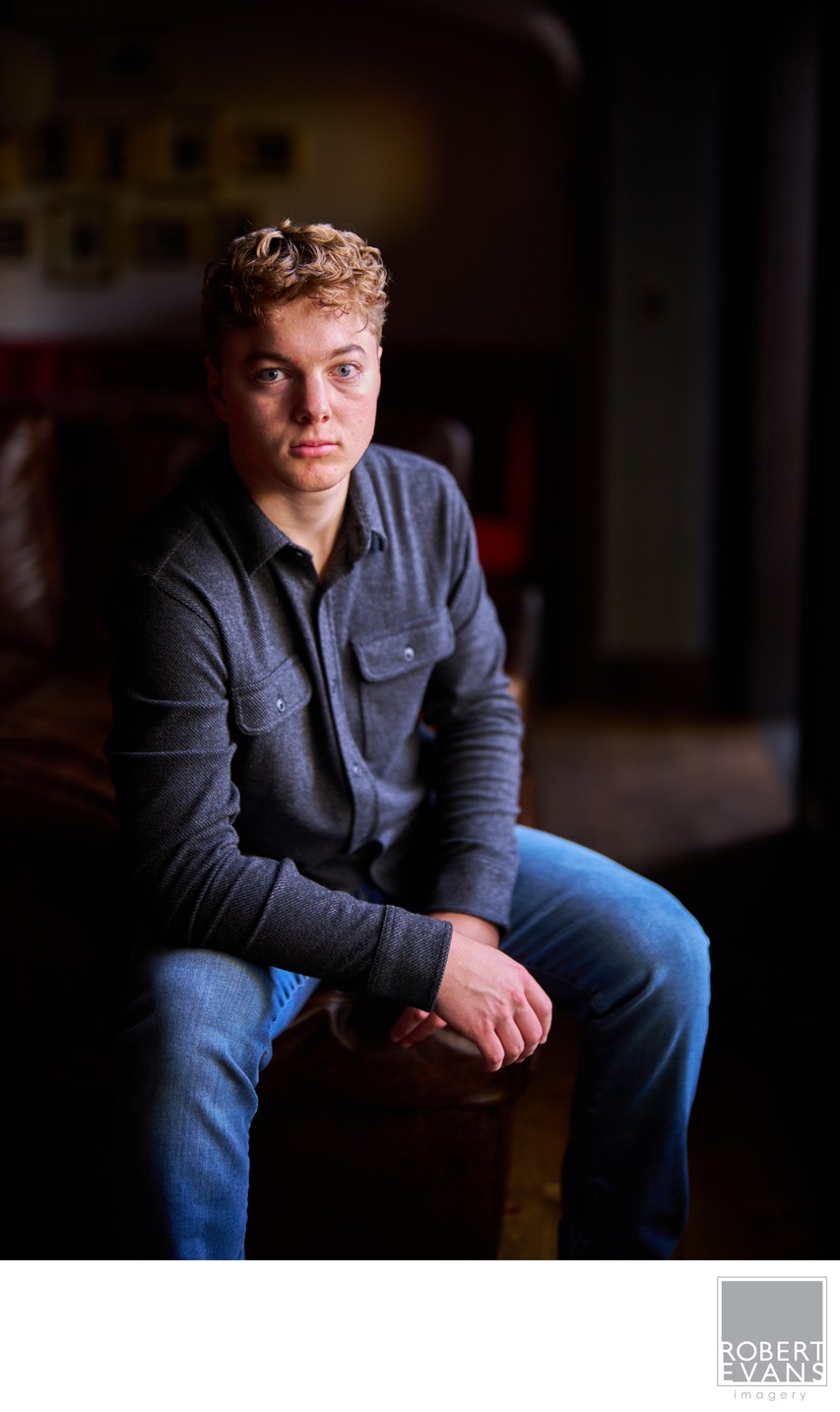 A young man sits indoors in soft directional light.