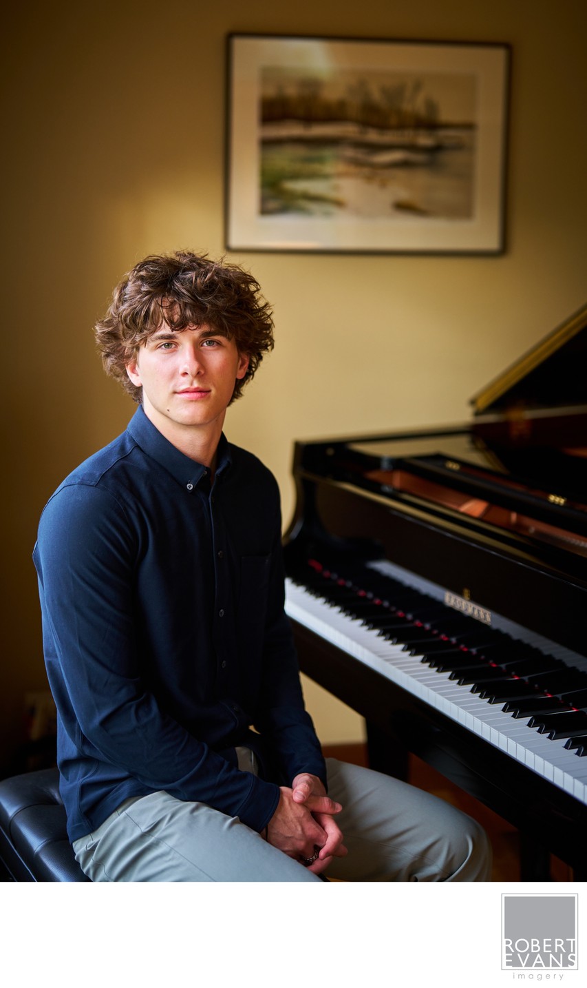 A curly-haired young man sits at a piano.