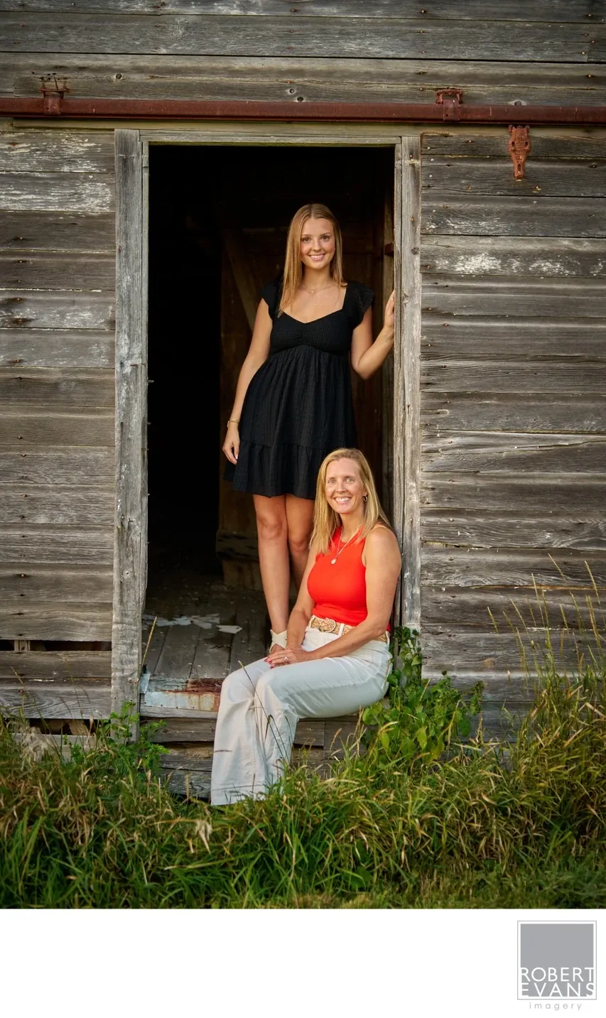 Two young women in black and orange outfits stand beside a rustic doorway.