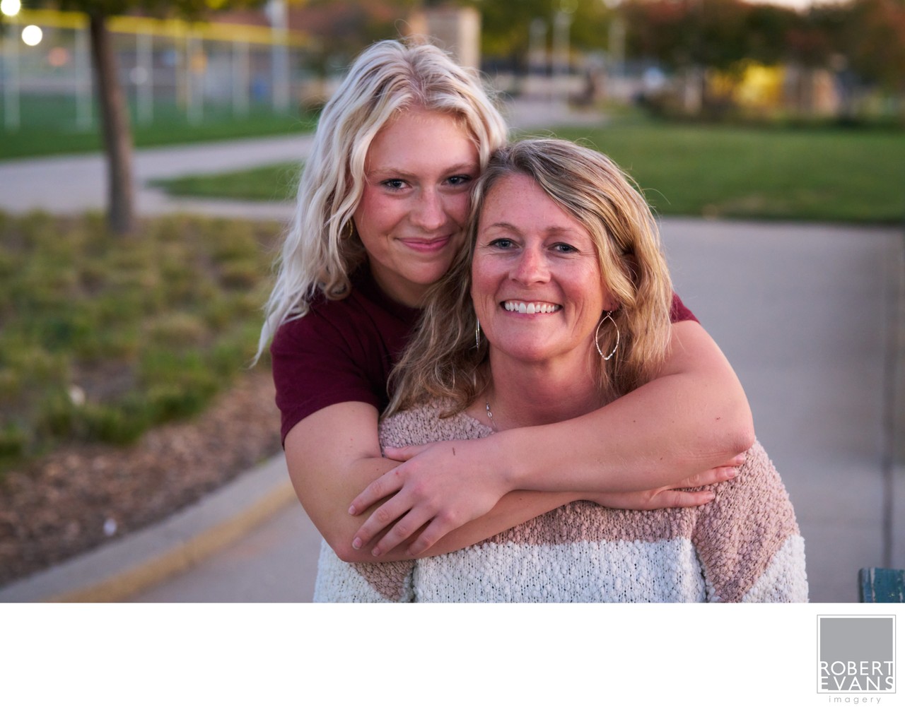 A mother and daughter embrace on an outdoor path.
