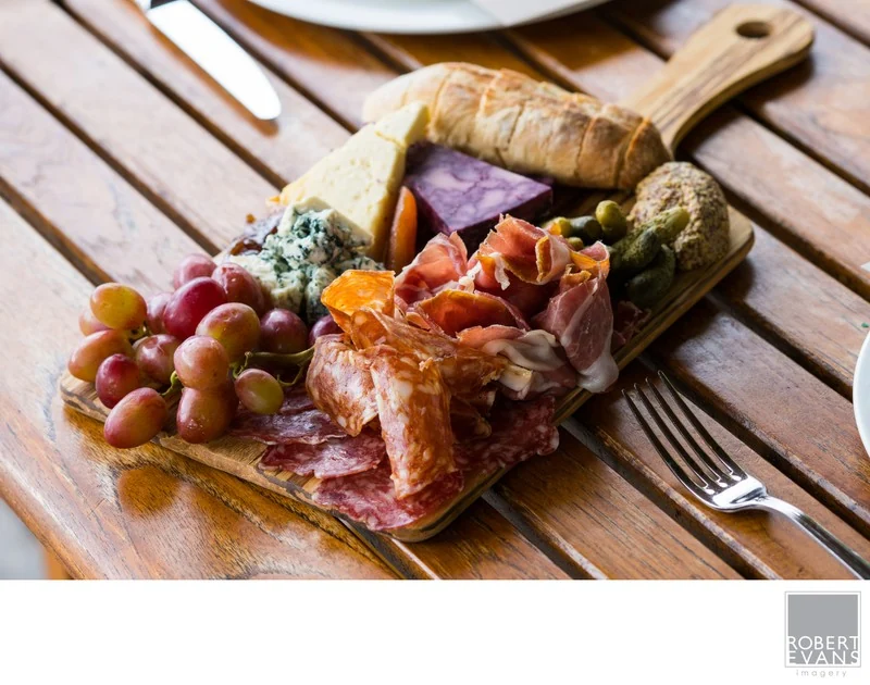 A grazing board of cheeses, fruit and charcuterie arranged on a wooden table.