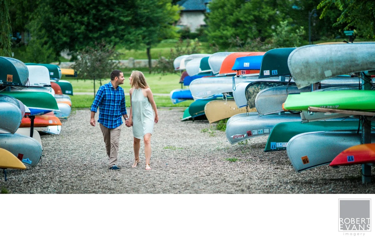 A couple walks hand in hand between colorful canoes.