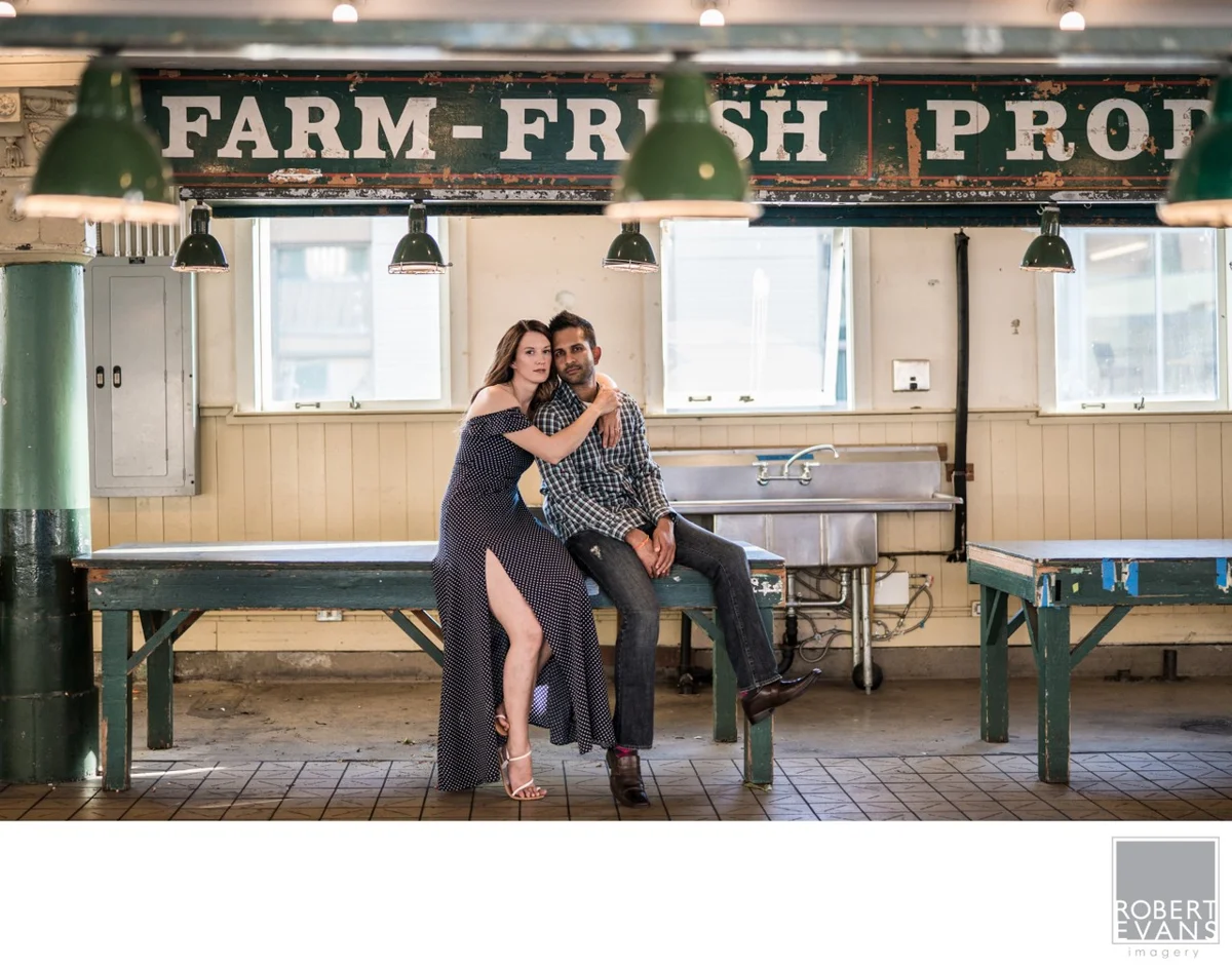 A couple sits together in front of a farm-fresh produce stand.