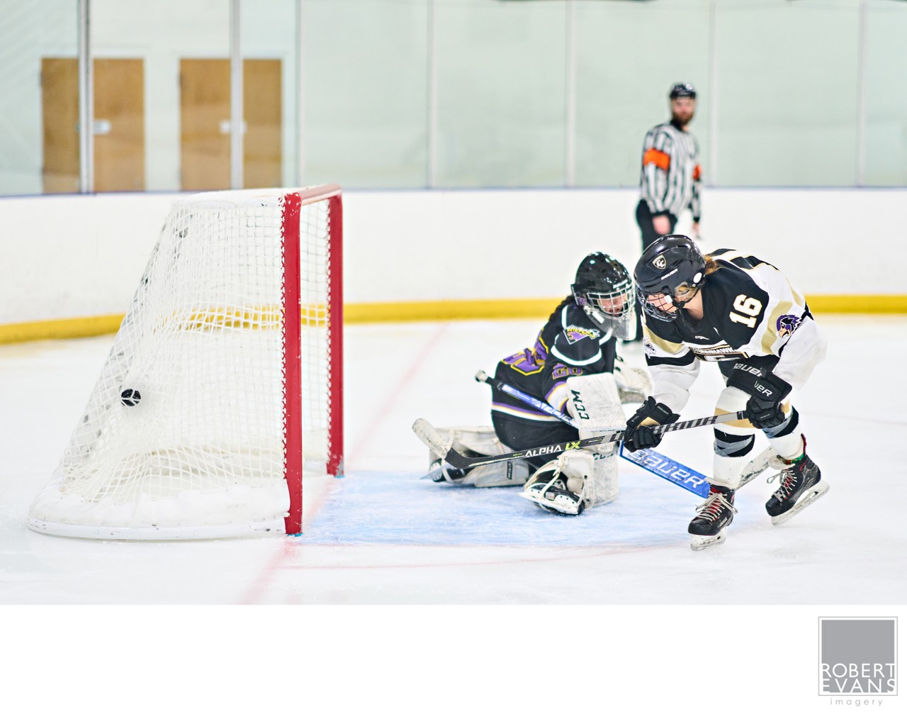 Hockey players crowd the crease as a goalie tracks the puck beside the net.