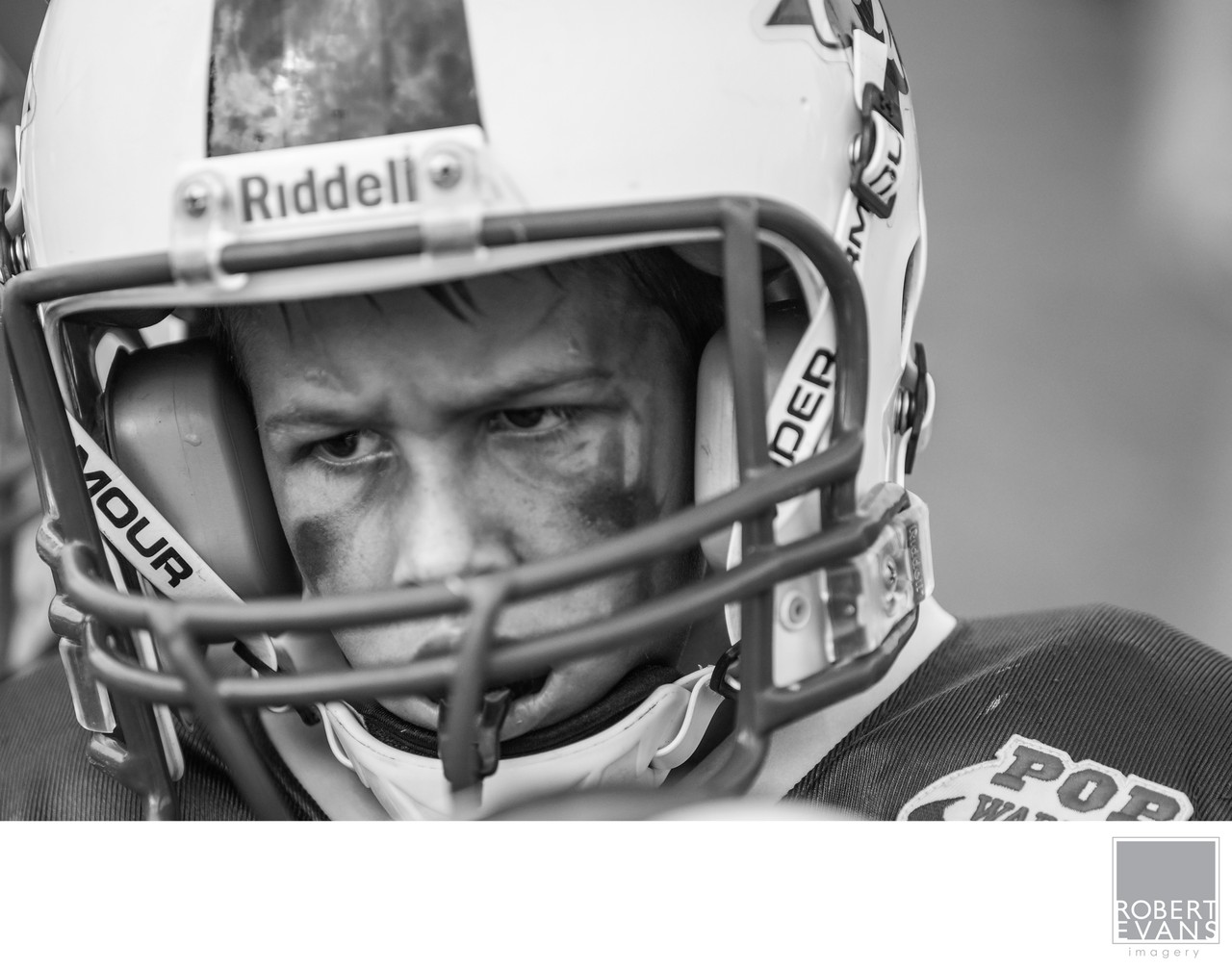 A close black-and-white portrait frames a young player’s eyes inside his helmet.