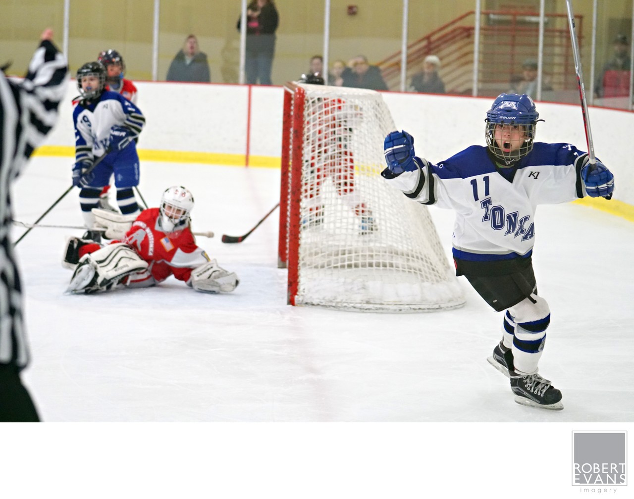 A white-and-blue player spreads his arms while skating away from the goal.