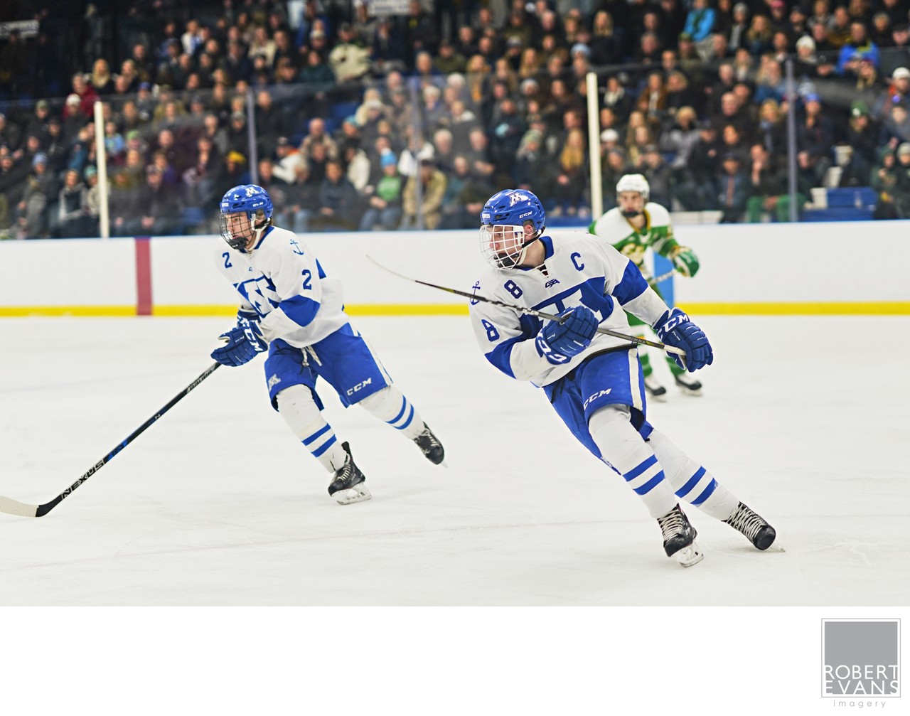 White-and-blue hockey teammates skate away together across the ice.