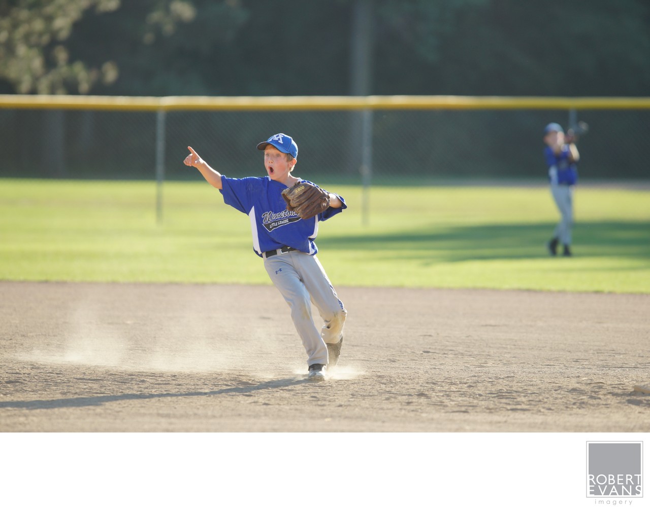 A youth baseball player steps into a throw across the dusty infield.