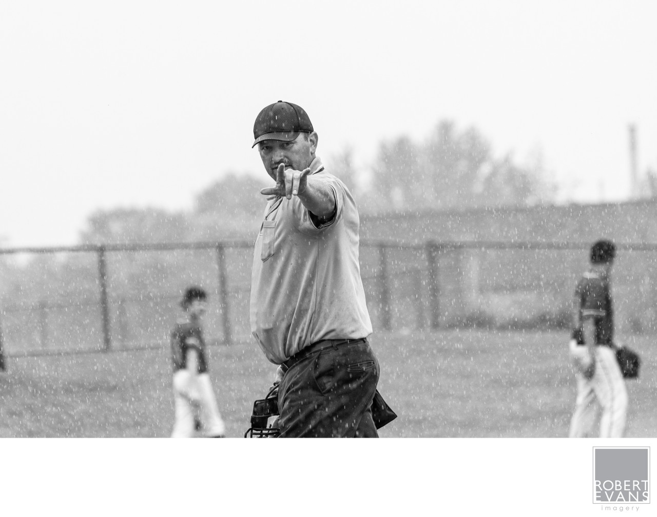 A baseball umpire points decisively across the field in black and white.