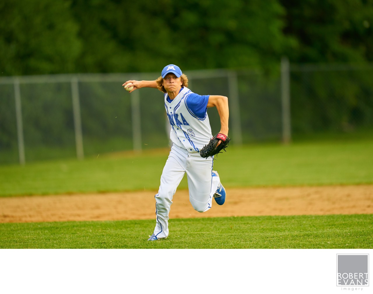 A pitcher in blue and white follows through with one leg lifted behind him.