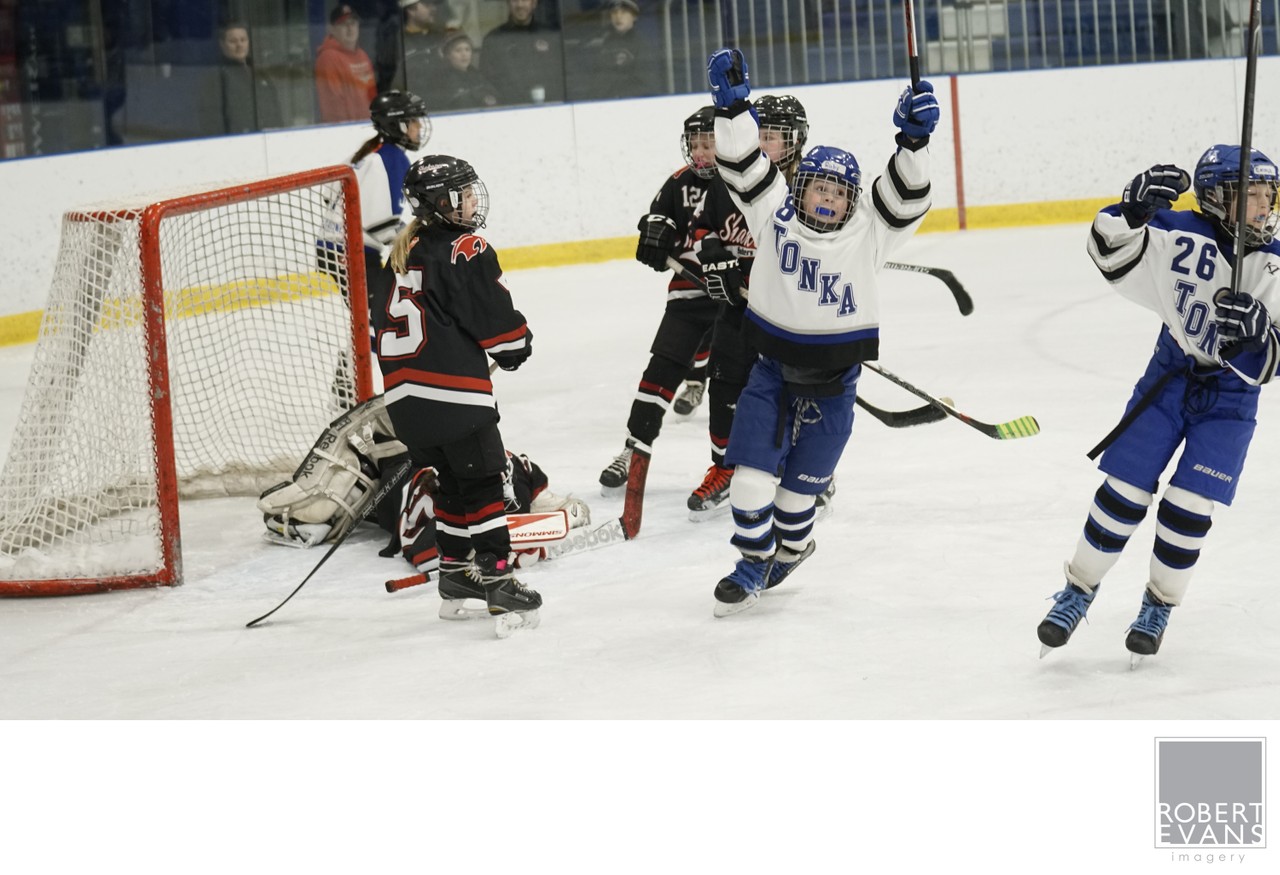 White-and-blue players raise their arms beside the net after a play.