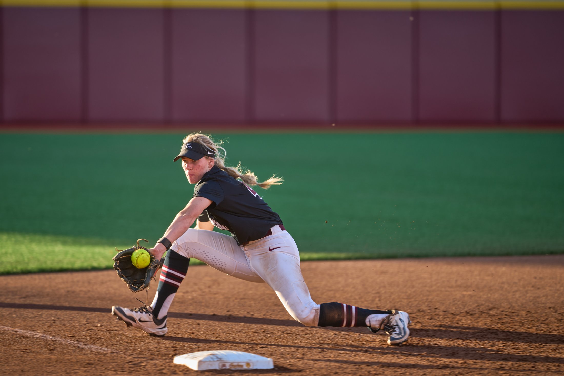 A Minnesota softball infielder stretches low to field the ball during a fall game against North Dakota State on October 4, 2026.