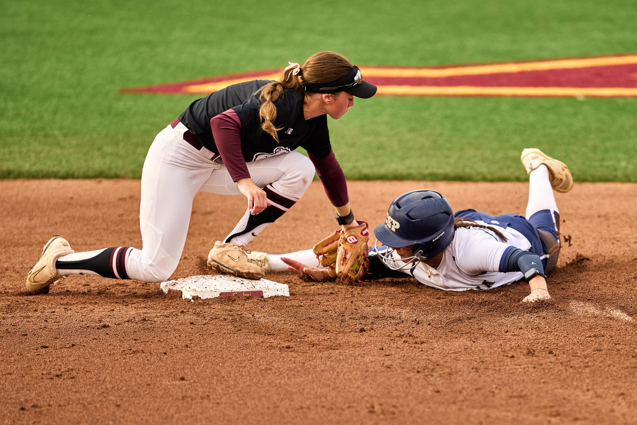 A Minnesota softball infielder reaches to tag a runner sliding headfirst toward the base during a fall game on September 27, 2026.