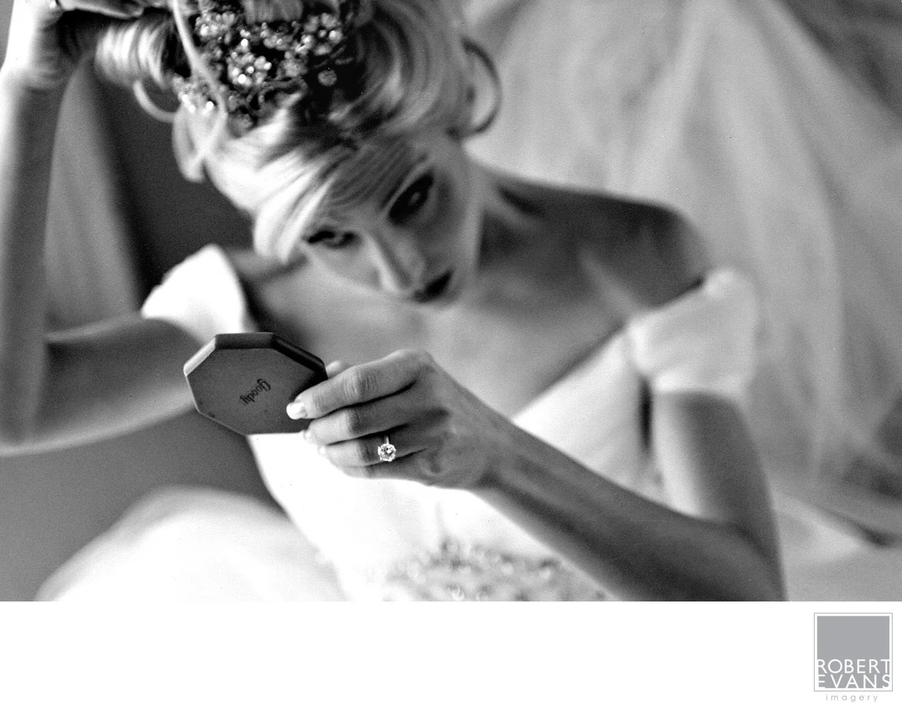 A bride looks down at a card held in her hands in a close black-and-white photograph.