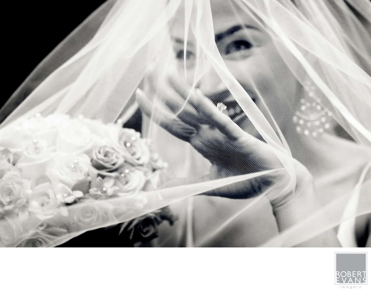 A close black-and-white detail shows a bride’s hand and rings beneath her veil beside flowers.
