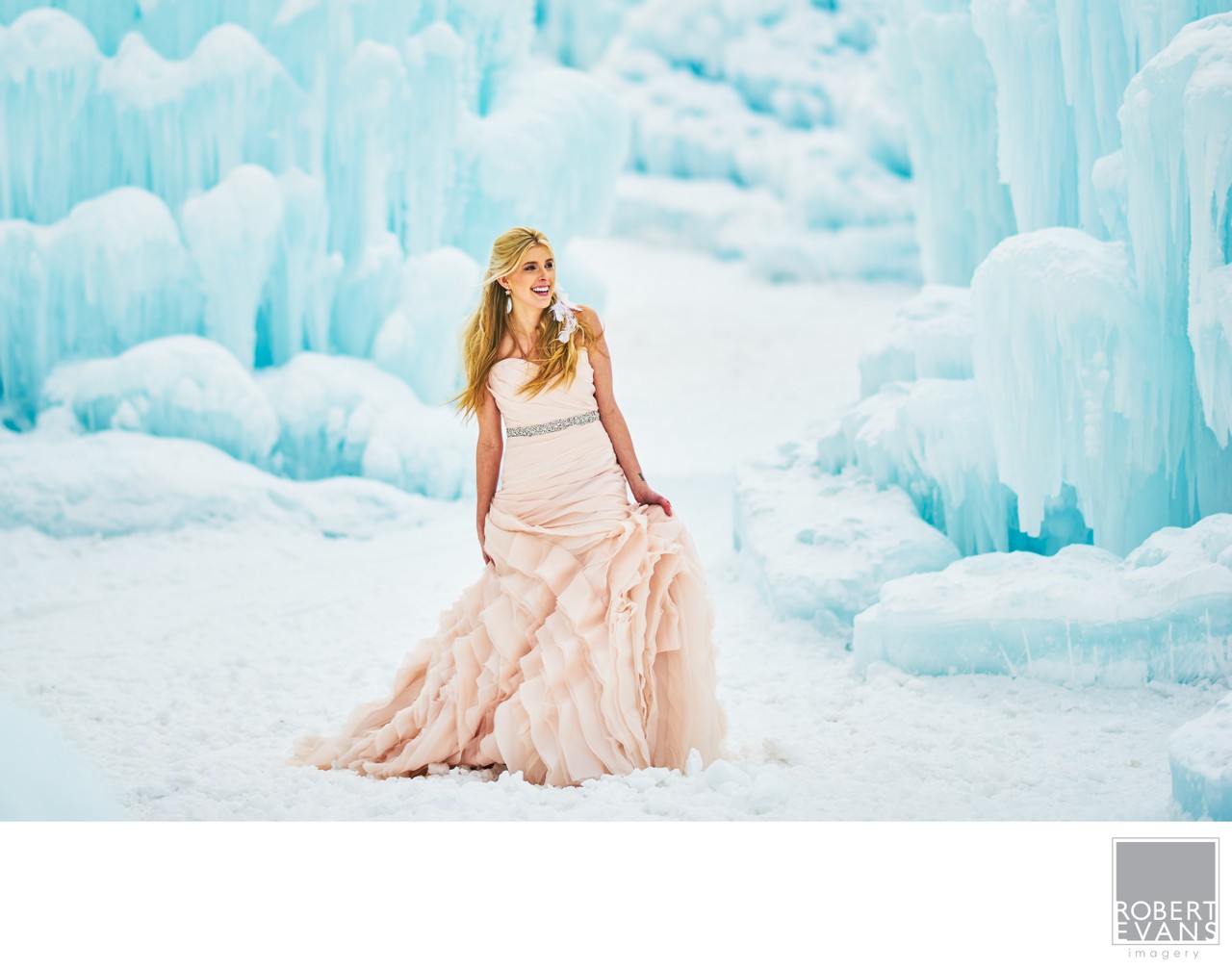 A bride sits in a flowing pale gown against blue ice walls.
