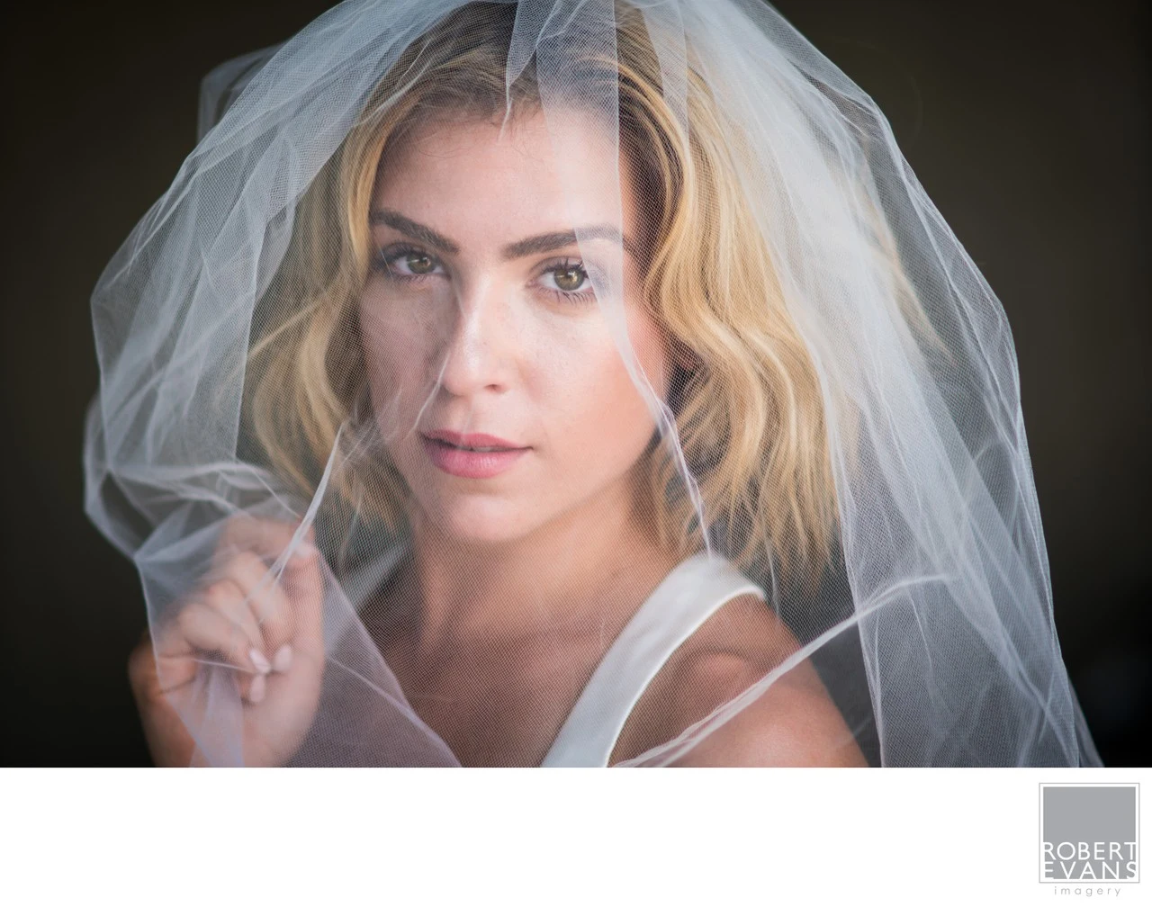 A bride looks toward the camera through soft layers of her sheer veil.