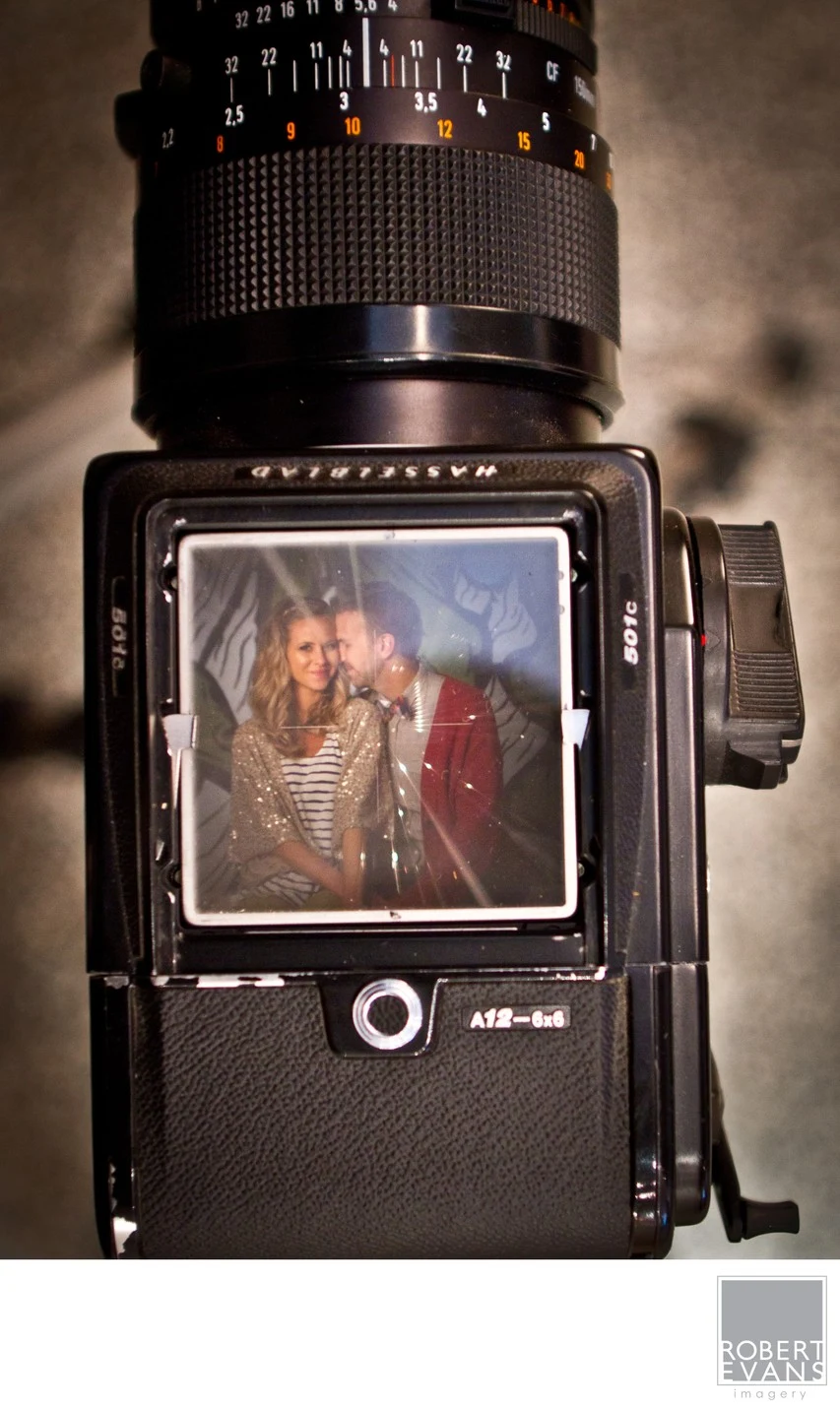 A couple appears in the waist-level viewfinder of a medium-format camera.