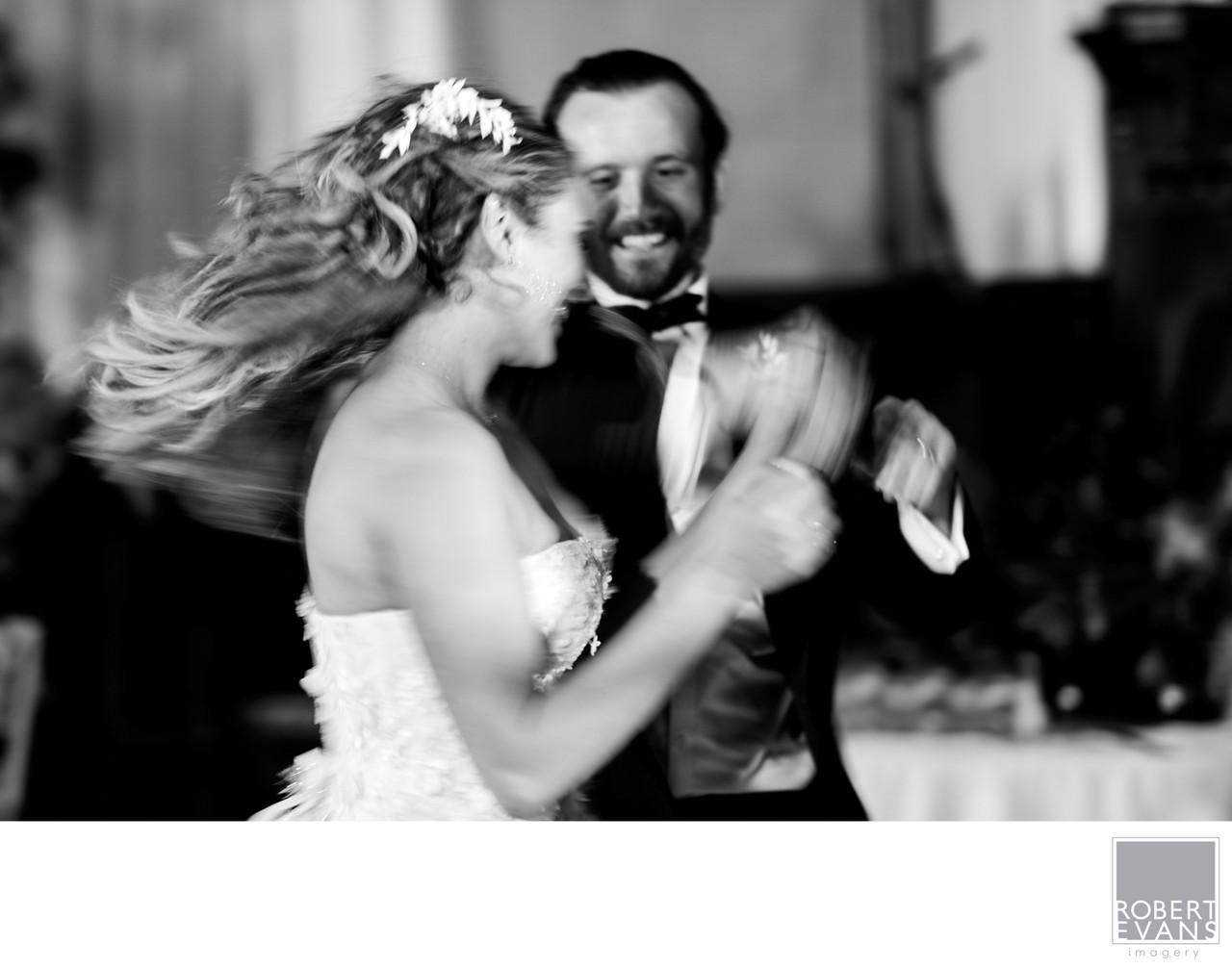 A bride’s hair sweeps outward as she dances with her groom in black and white.