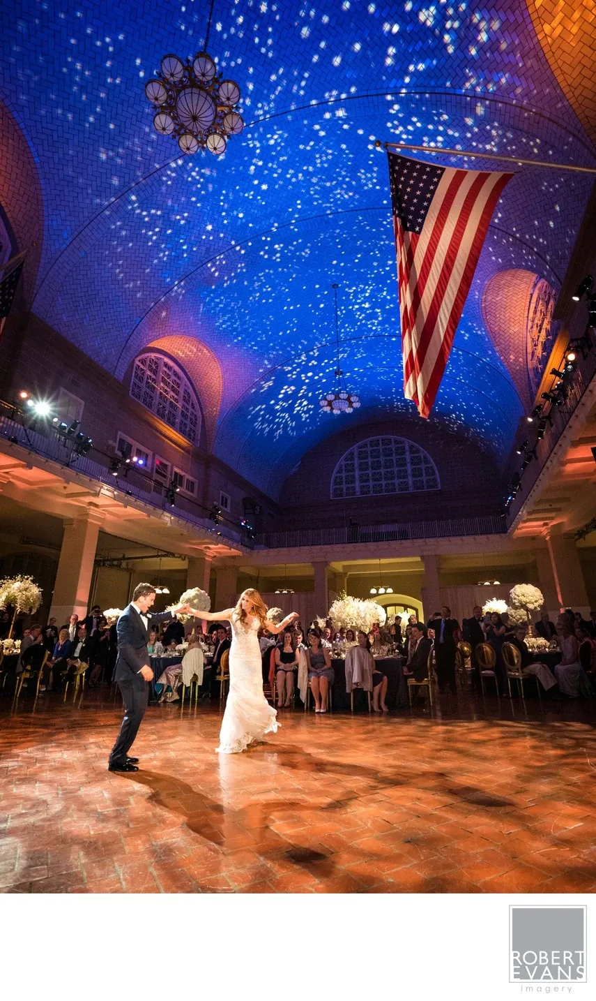 A wedding couple dances beneath a richly decorated blue ceiling and hanging flags.
