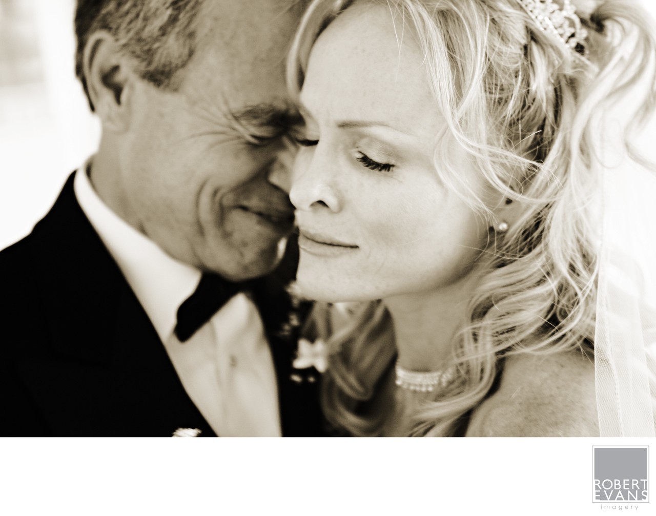 A bride and groom rest their faces together with eyes lowered in a tender monochrome close-up.