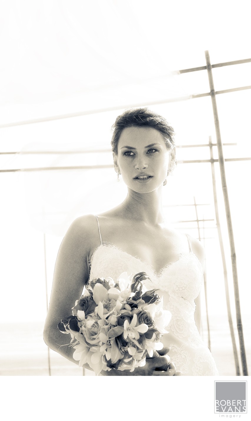 A bride holds her bouquet while standing before geometric window frames in black and white.