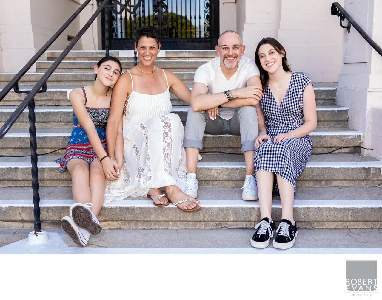 Four people sit together on broad steps outside a building in a casual group portrait.