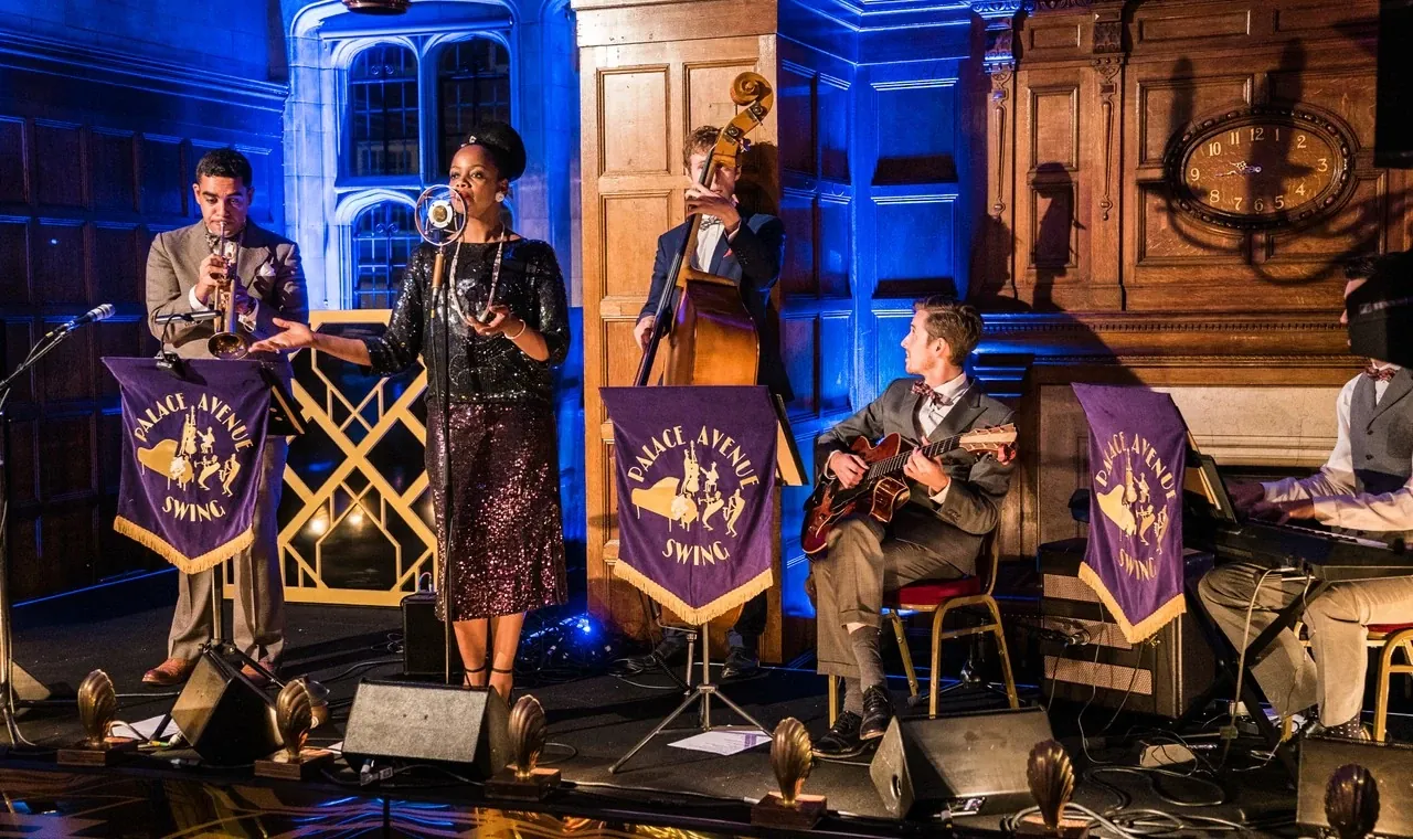 A small band performs with a singer and musicians under blue stage lighting.