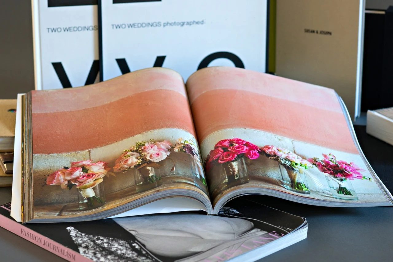 An open photography album displays colorful floral wedding details across a two-page spread.