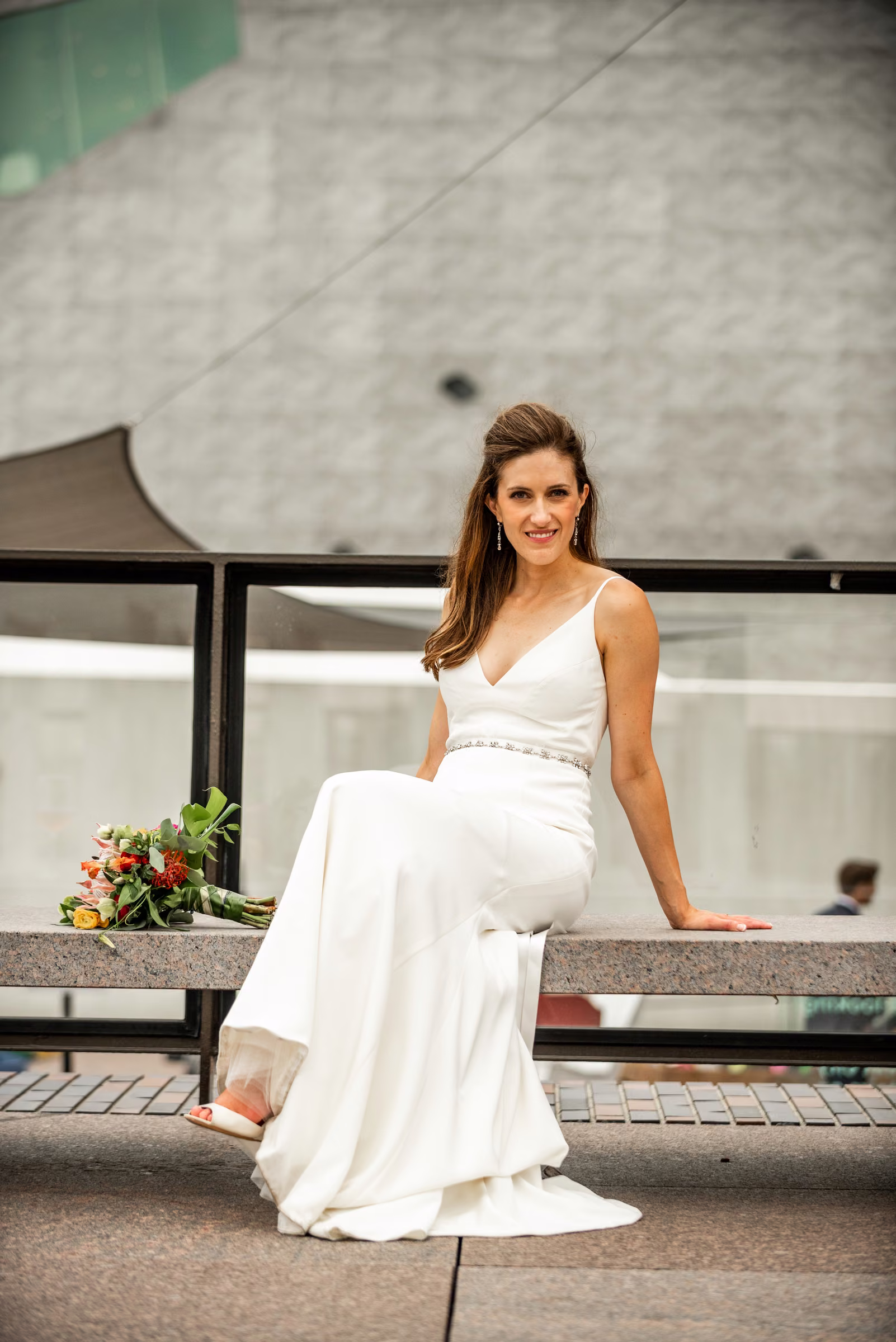 Ali sits in her wedding dress beside the Walker Art Center’s modern concrete walls and terrace railings