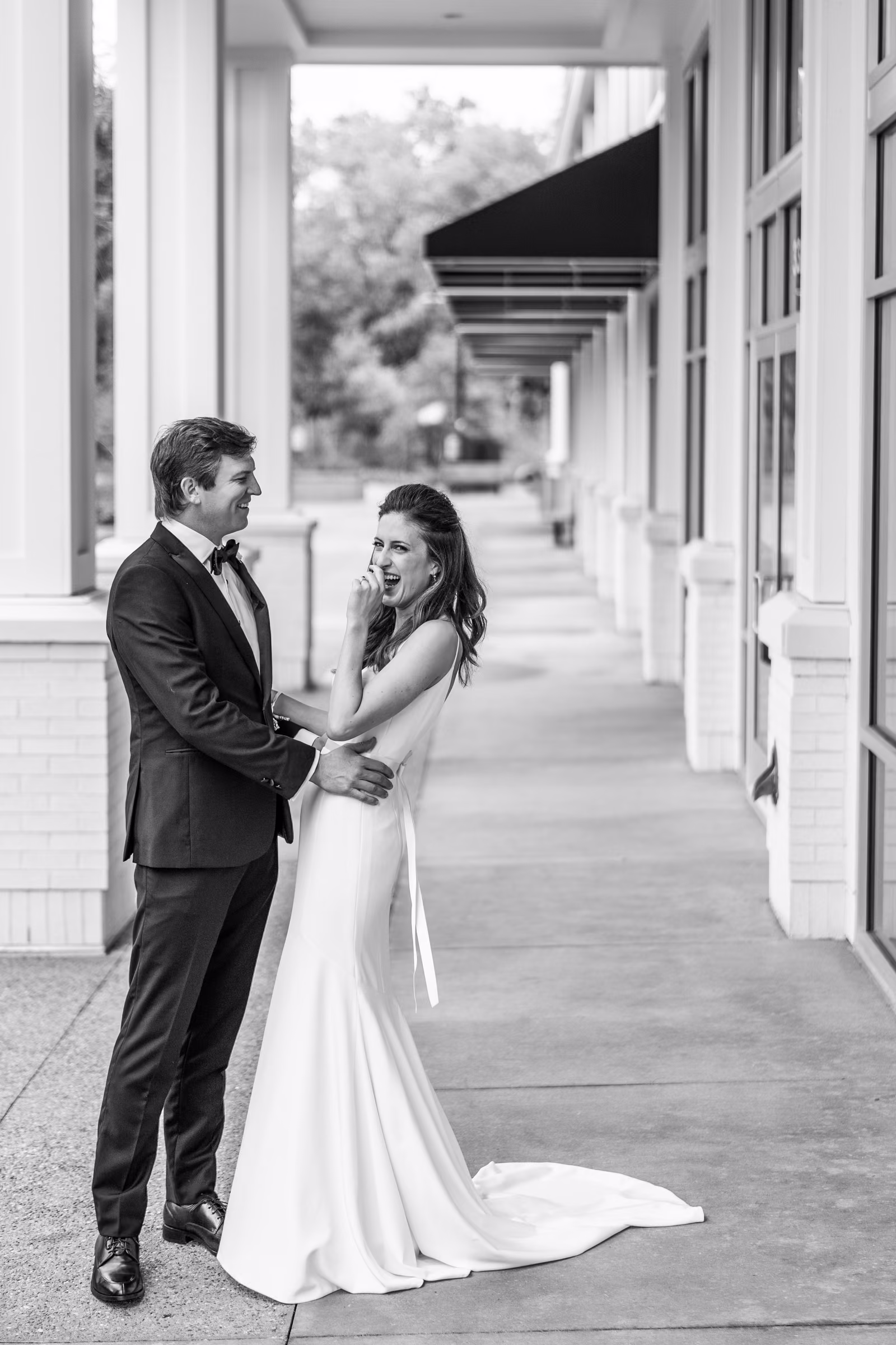 Black-and-white portrait of Ali and Drew holding hands beneath the hotel awning