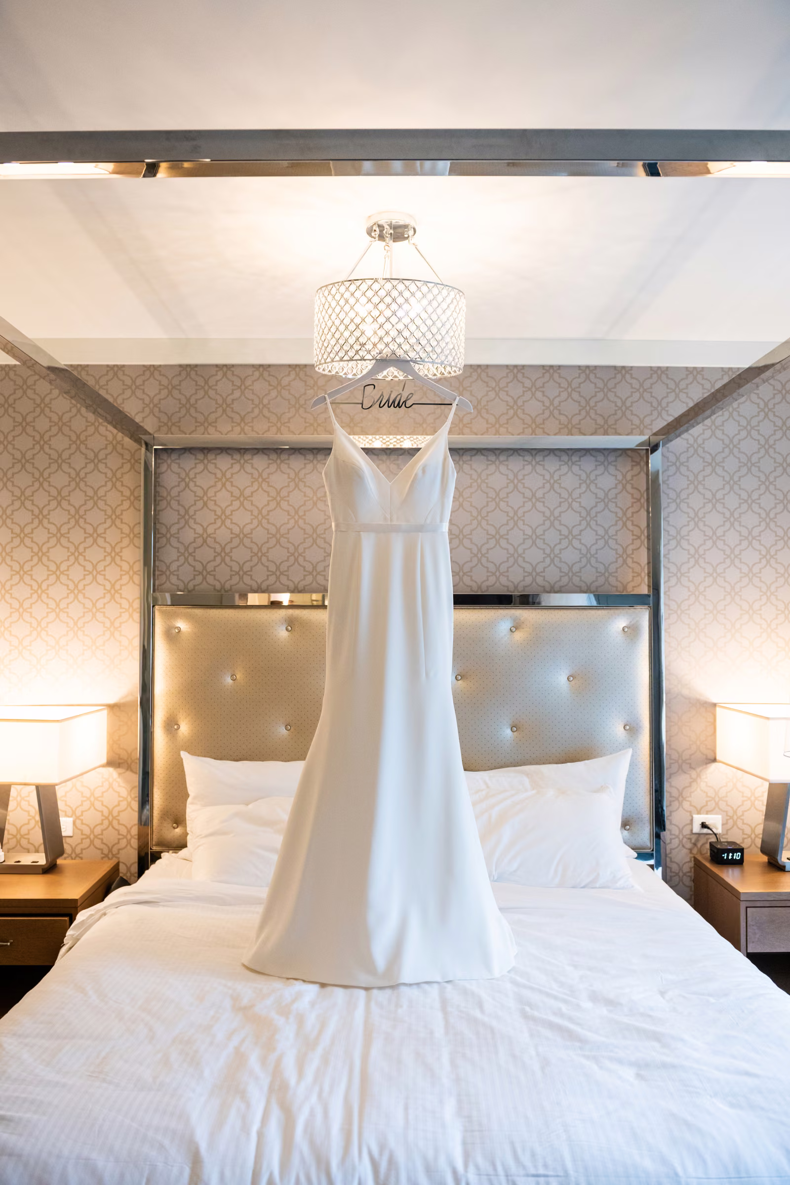 Ali’s wedding dress hangs above the bed in a softly lit room at The Hotel Landing