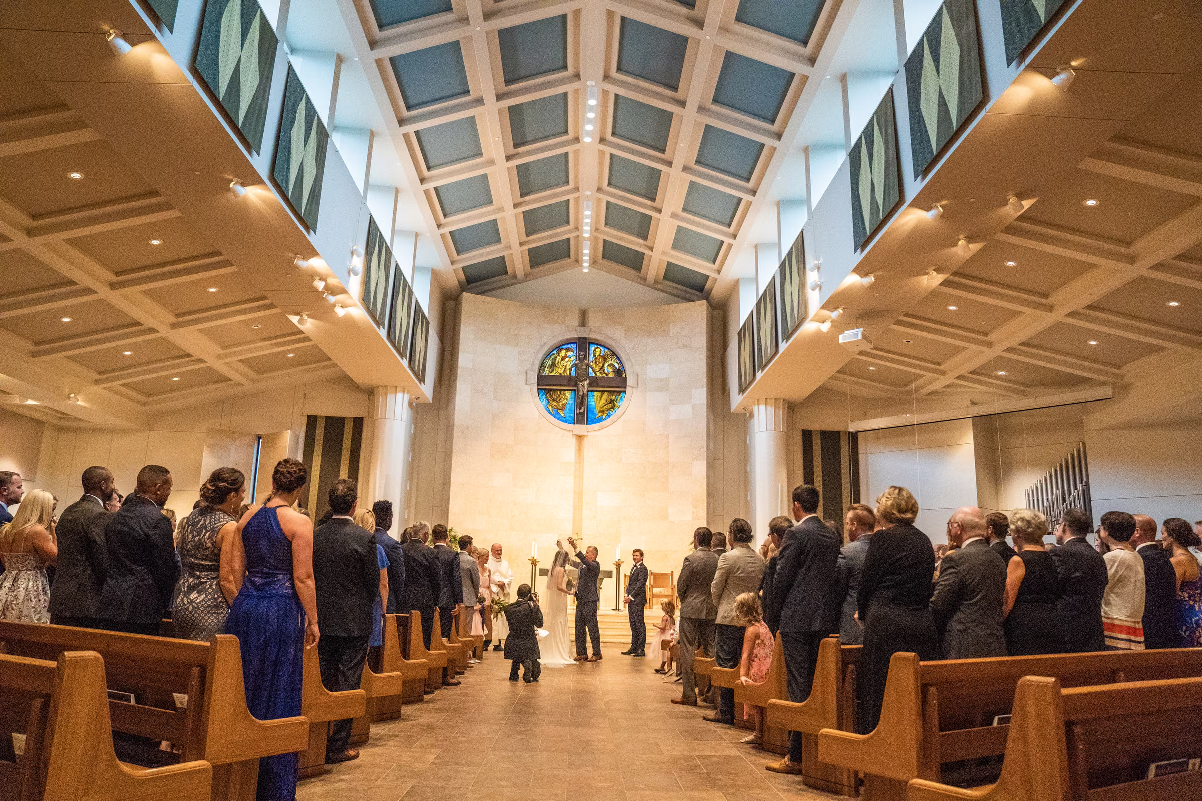 Guests stand in the bright church aisle as Ali and her father arrive at the front of the ceremony