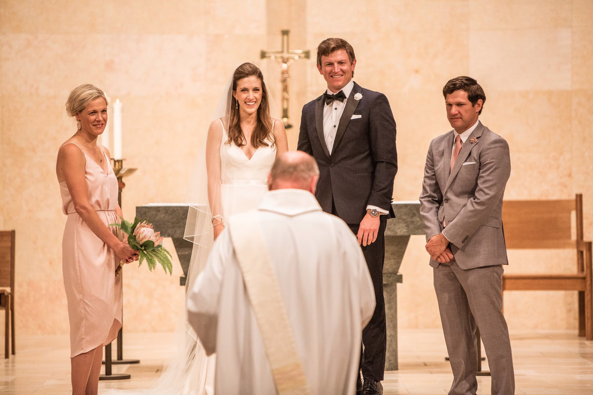 Ali and Drew face the officiant at the altar with their attendants beside them