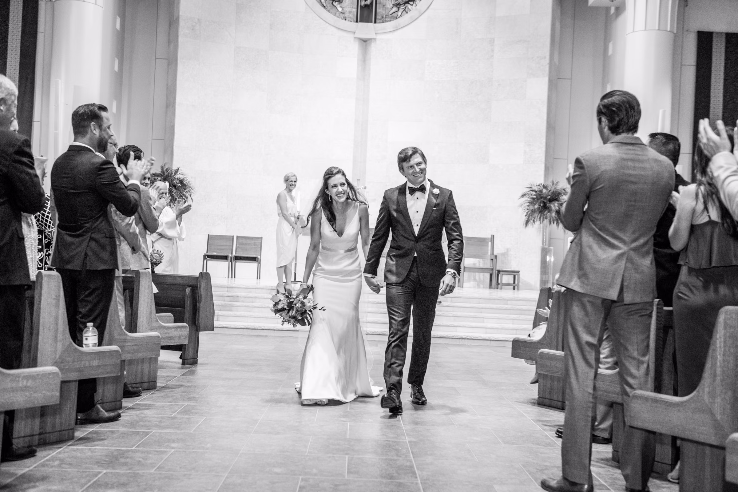 Ali and Drew smile while walking back down the church aisle as guests applaud