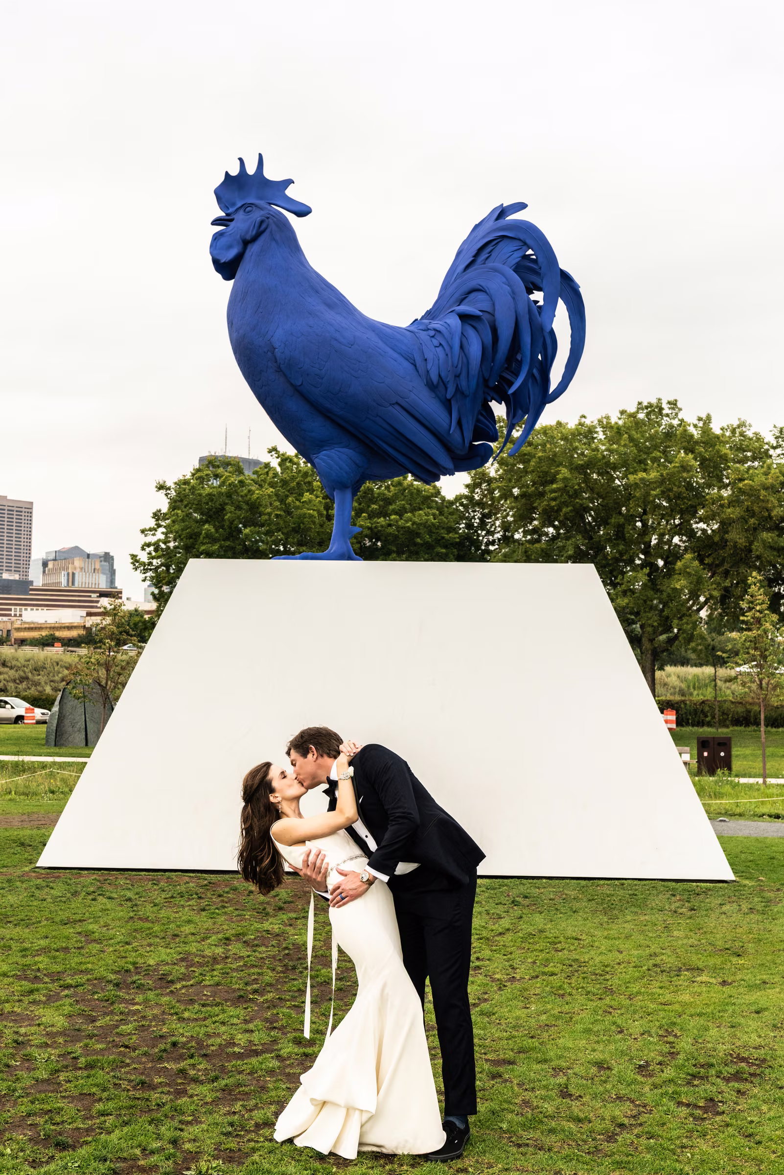 Drew dips and kisses Ali beneath the giant blue rooster sculpture