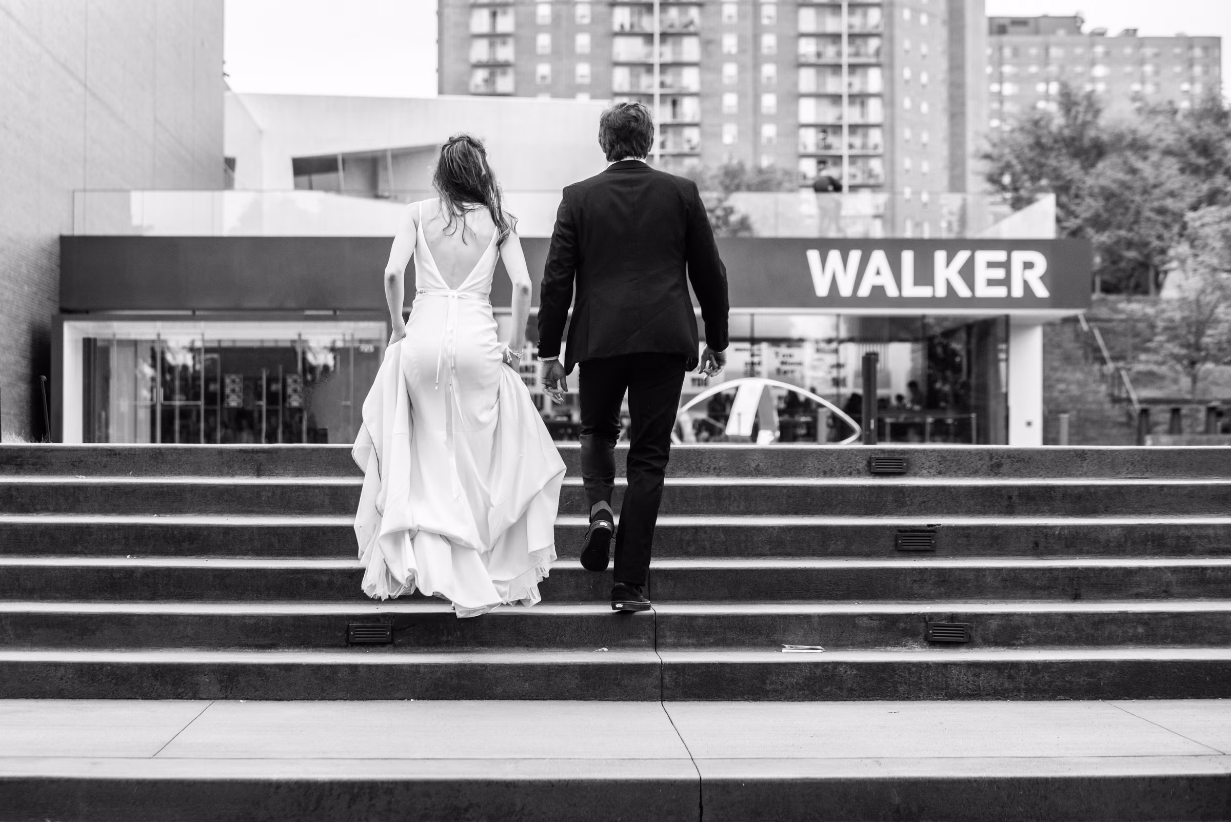 Black-and-white photograph of Ali and Drew climbing the steps toward the Walker Art Center entrance