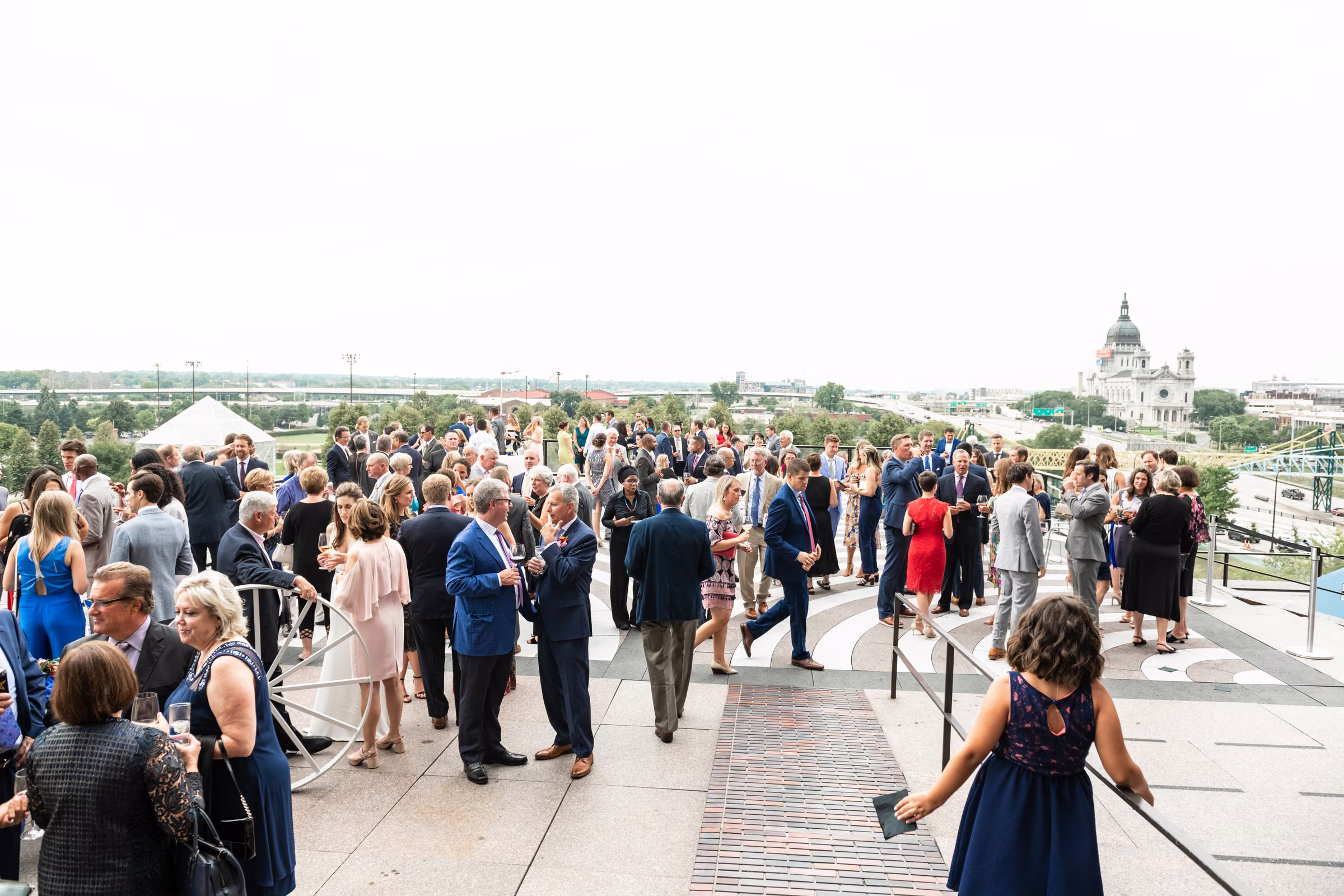Wedding guests gather on the Walker terrace with the Minneapolis skyline and Basilica of Saint Mary behind them