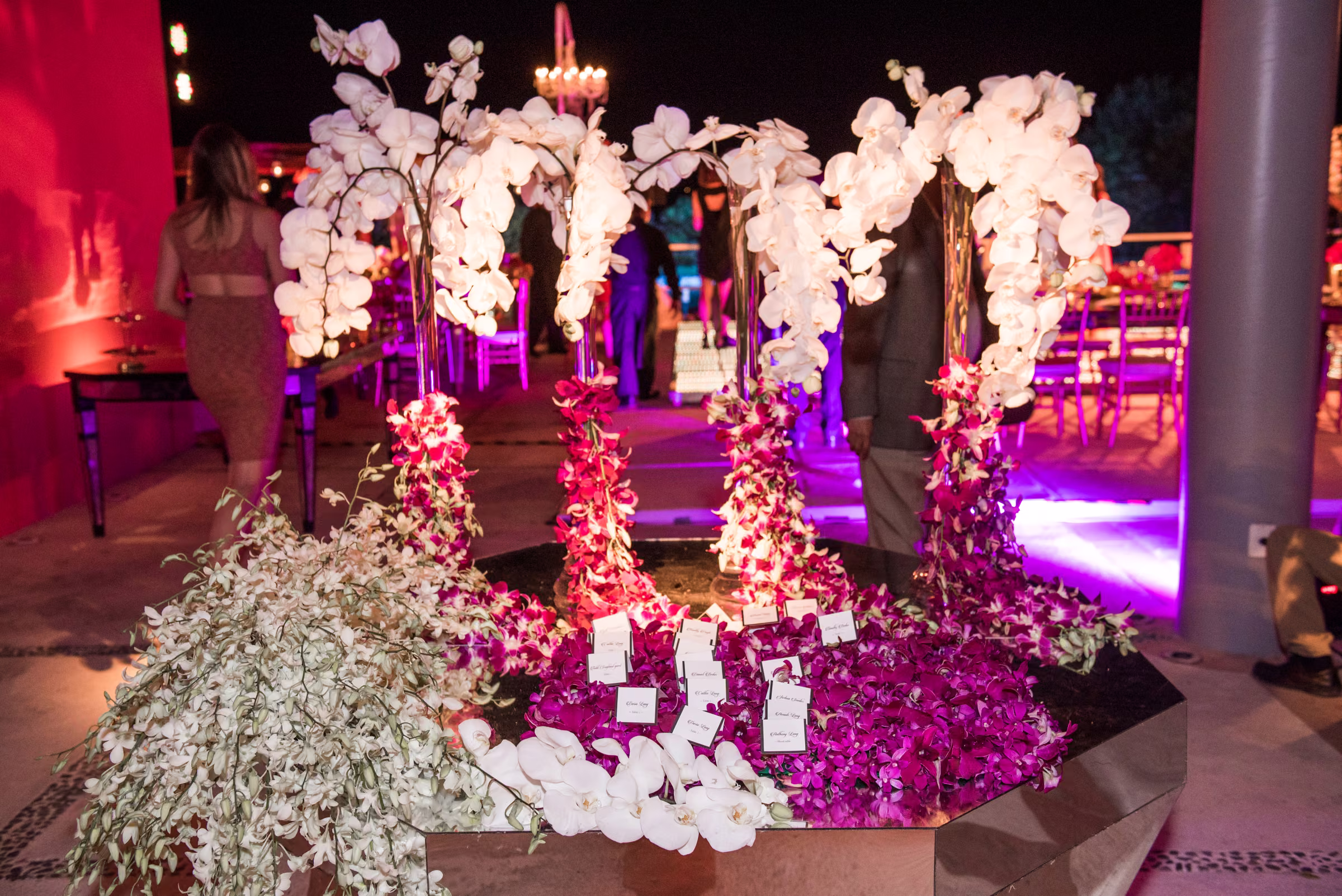 White and bright pink floral garlands are arranged beneath orchid centerpieces