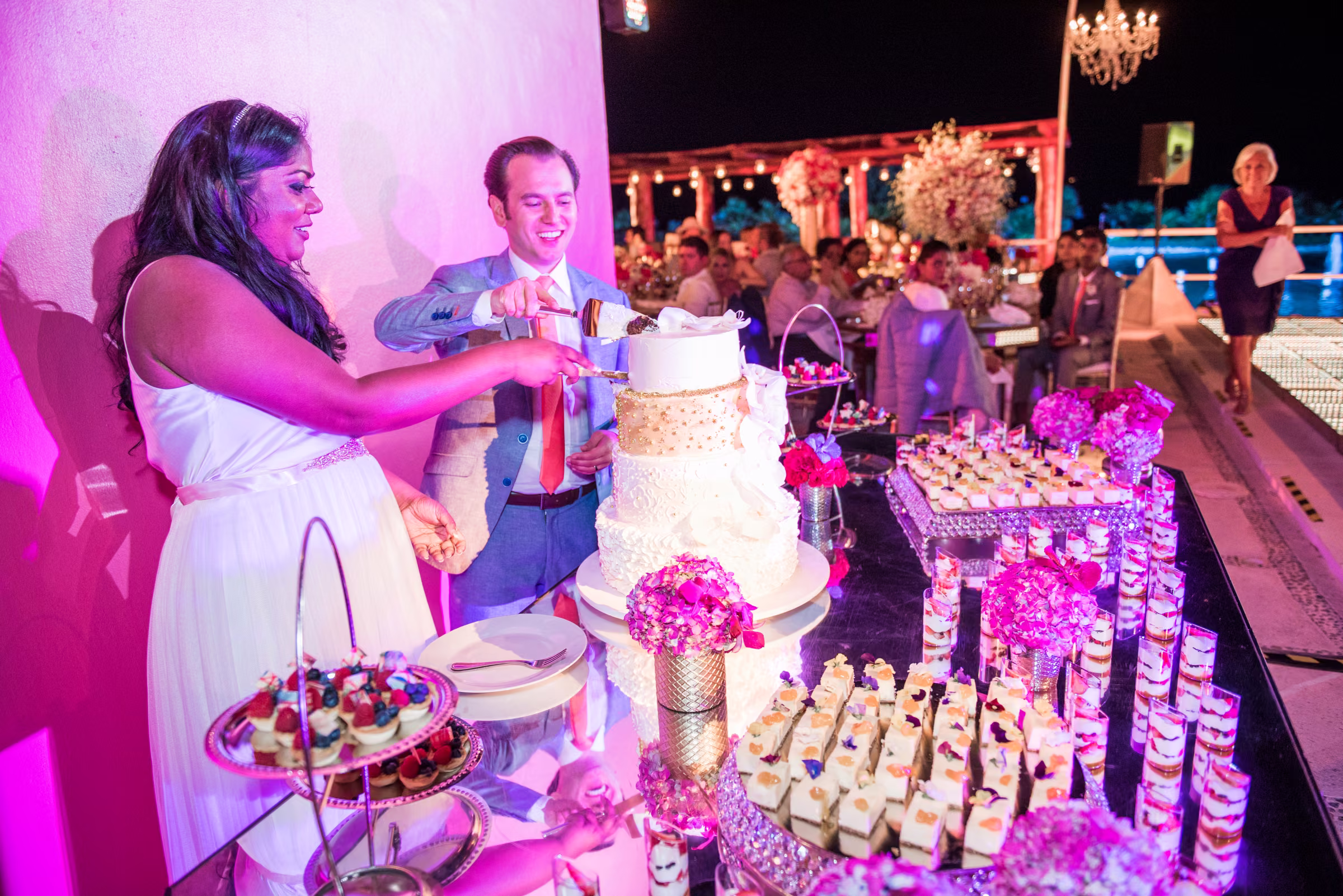 Avanti and Tony laugh while cutting their wedding cake together